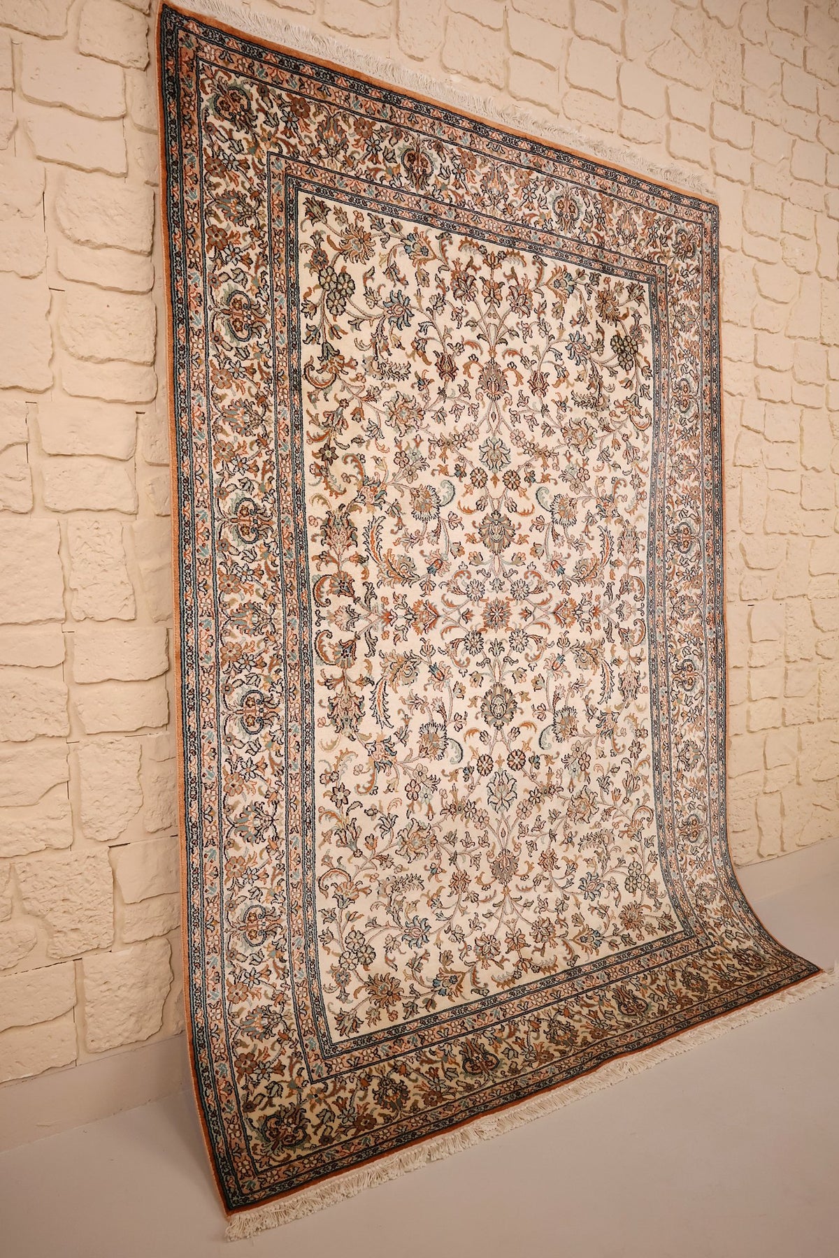 Tapis Cachemire ivoire vu de biais, bordure fleurie et franges écrues
