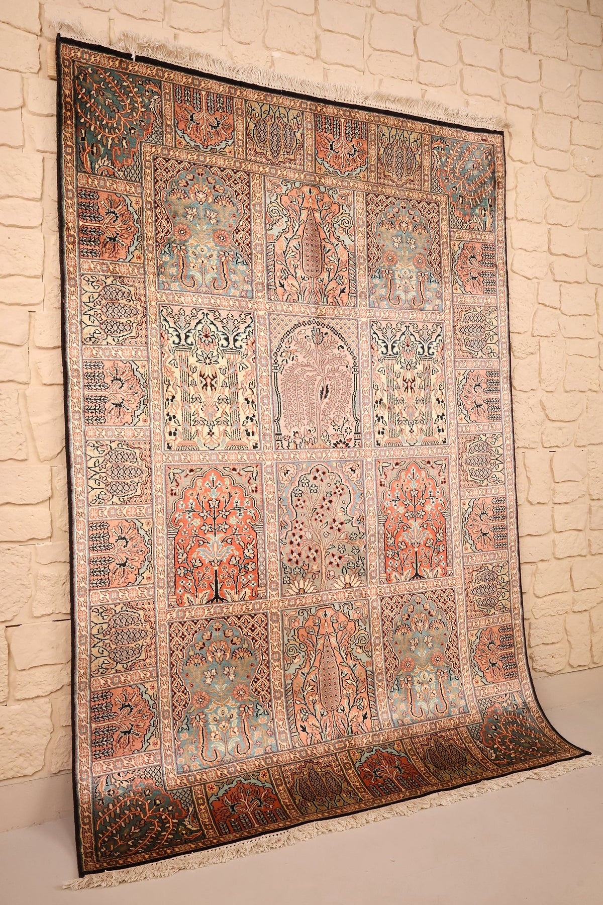 Tapis Cachemire en soie noué main, vue de biais contre un mur clair