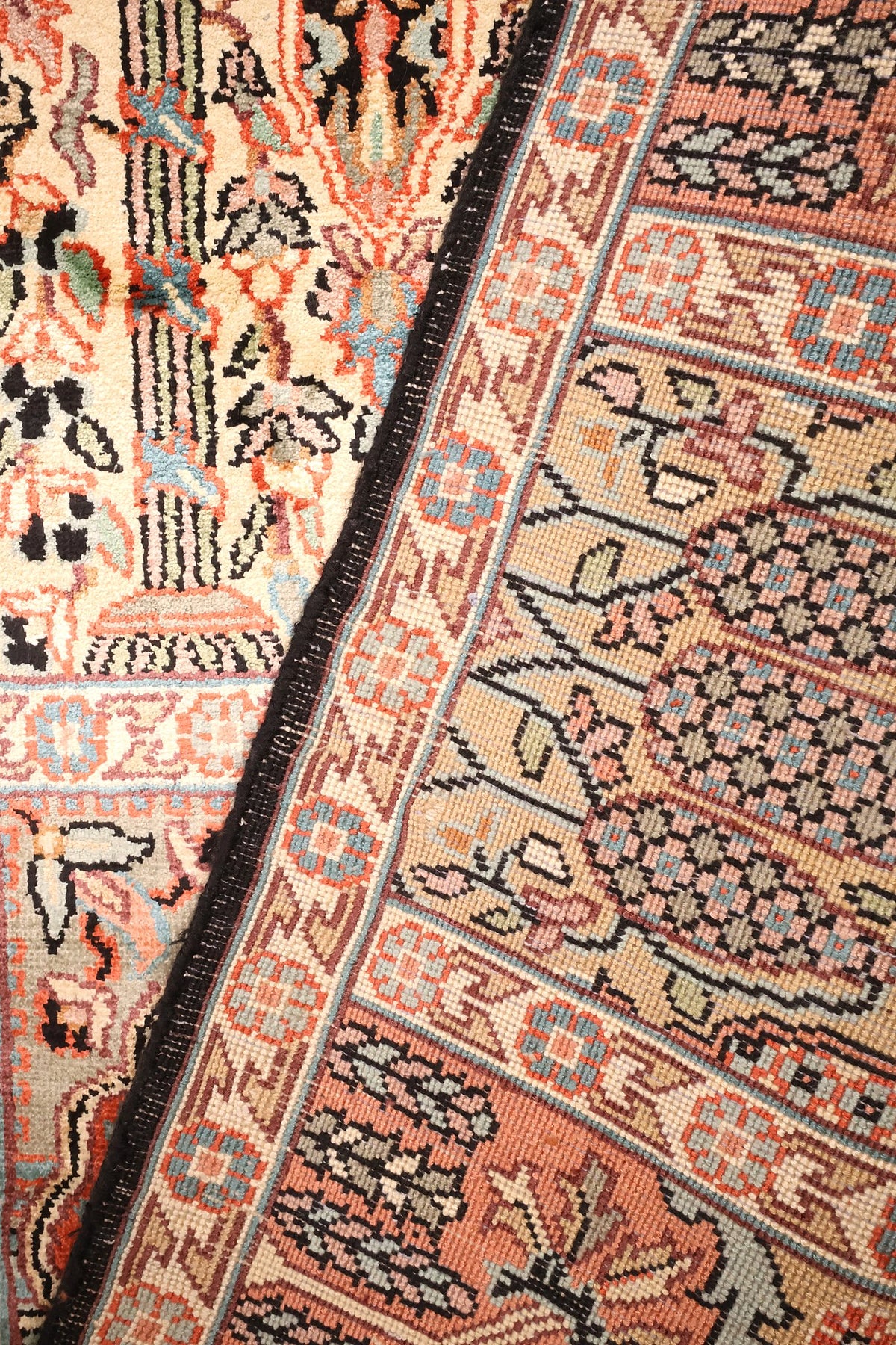 Coin replié du tapis Cachemire, lisière sombre et cases beige et bleu