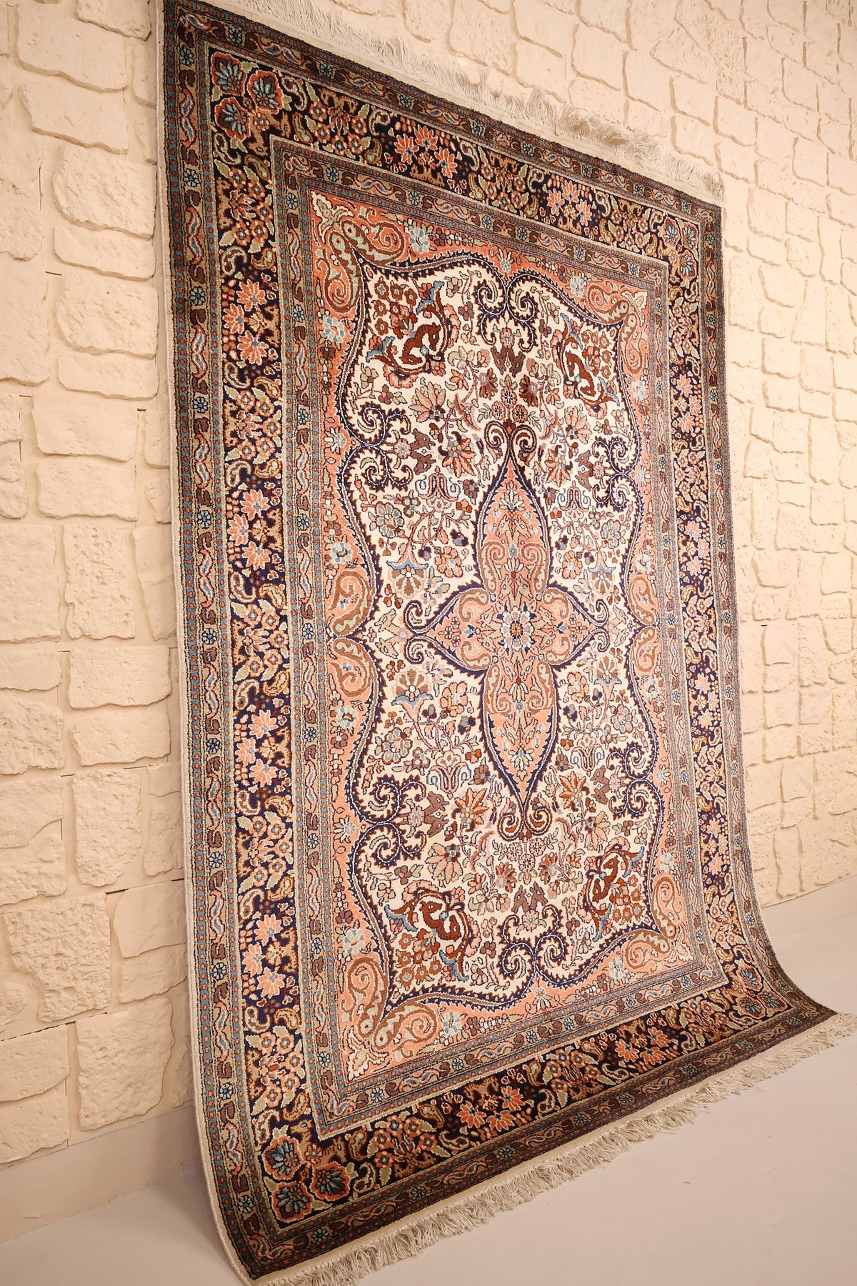 Tapis Cachemire beige et orange vu de biais, champ ivoire fleuri et bordure bleu nuit