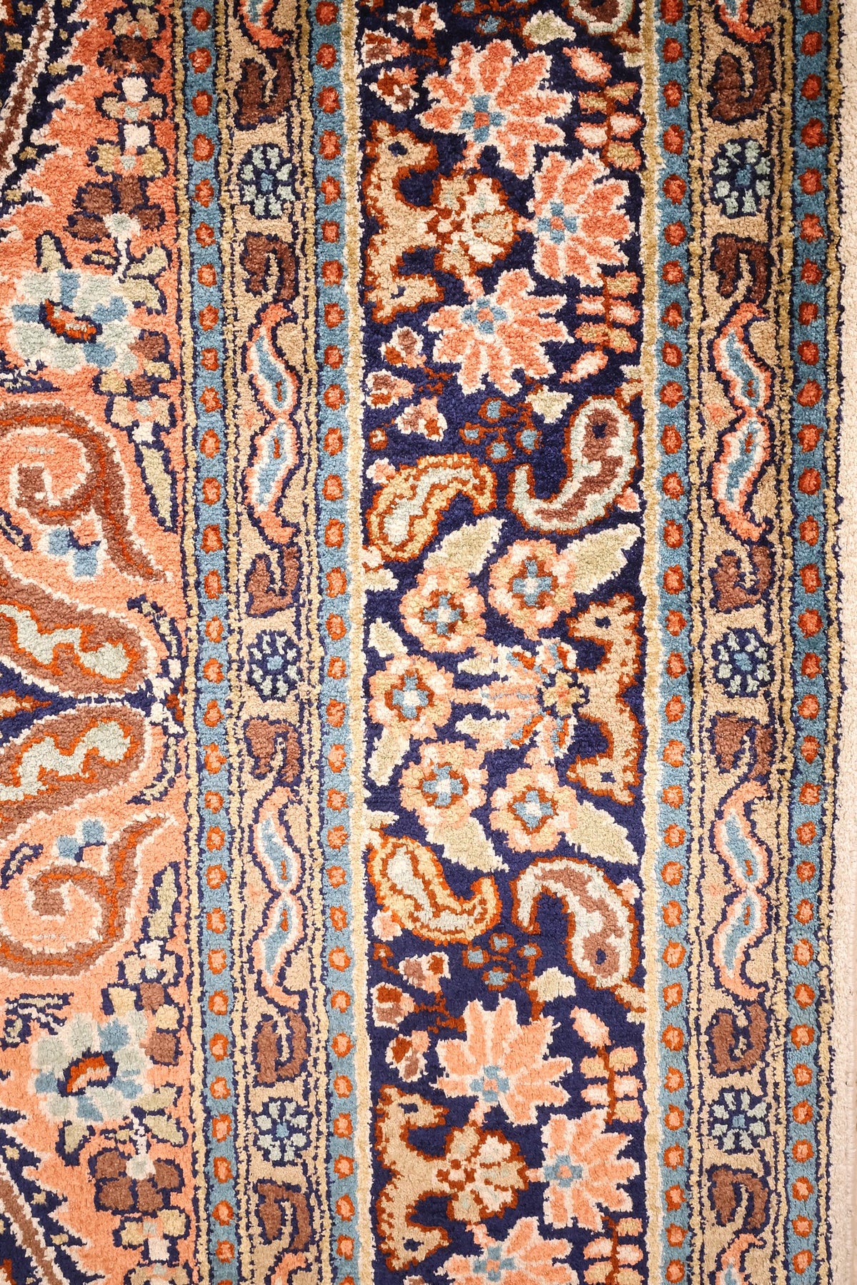 Gros plan des contre-bordures beige et bleu du tapis Cachemire en soie
