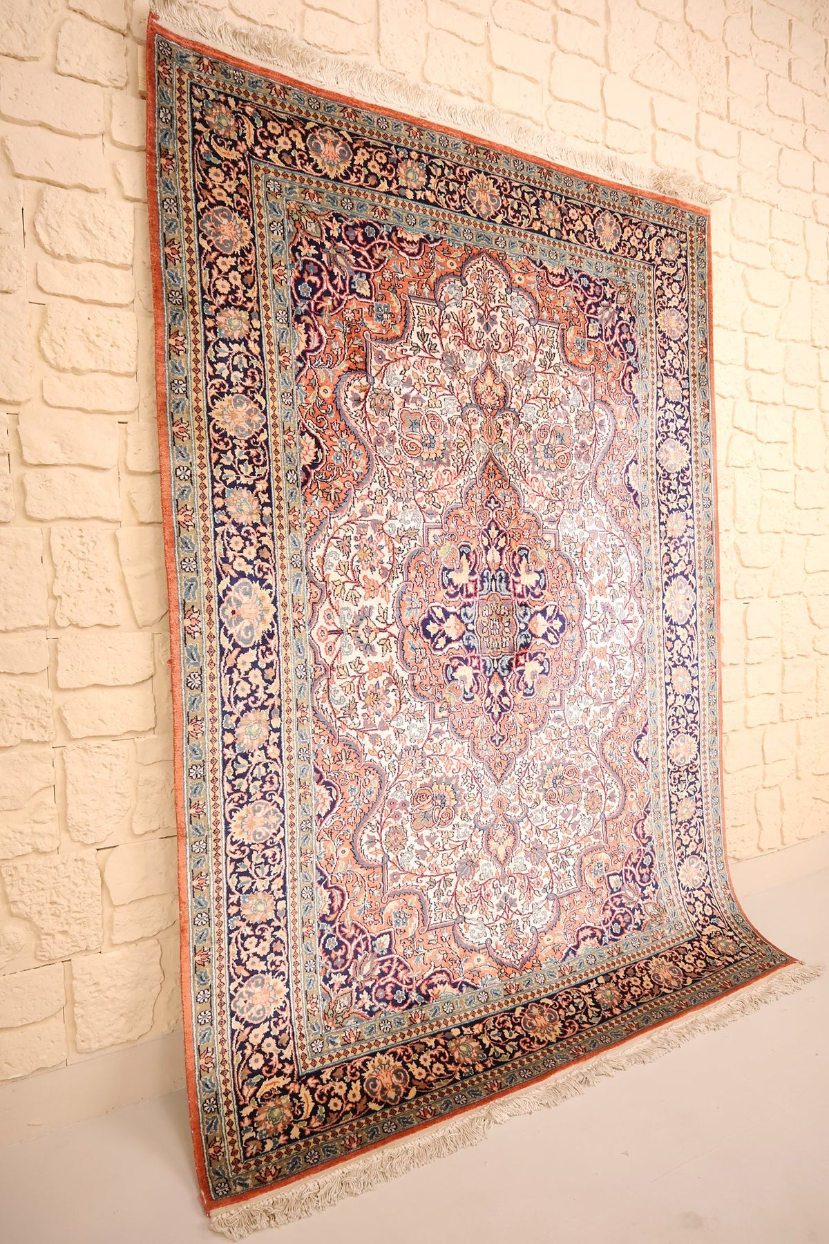 Tapis Cachemire en soie noué à la main, vue de biais du champ saumon et des bordures bleu marine