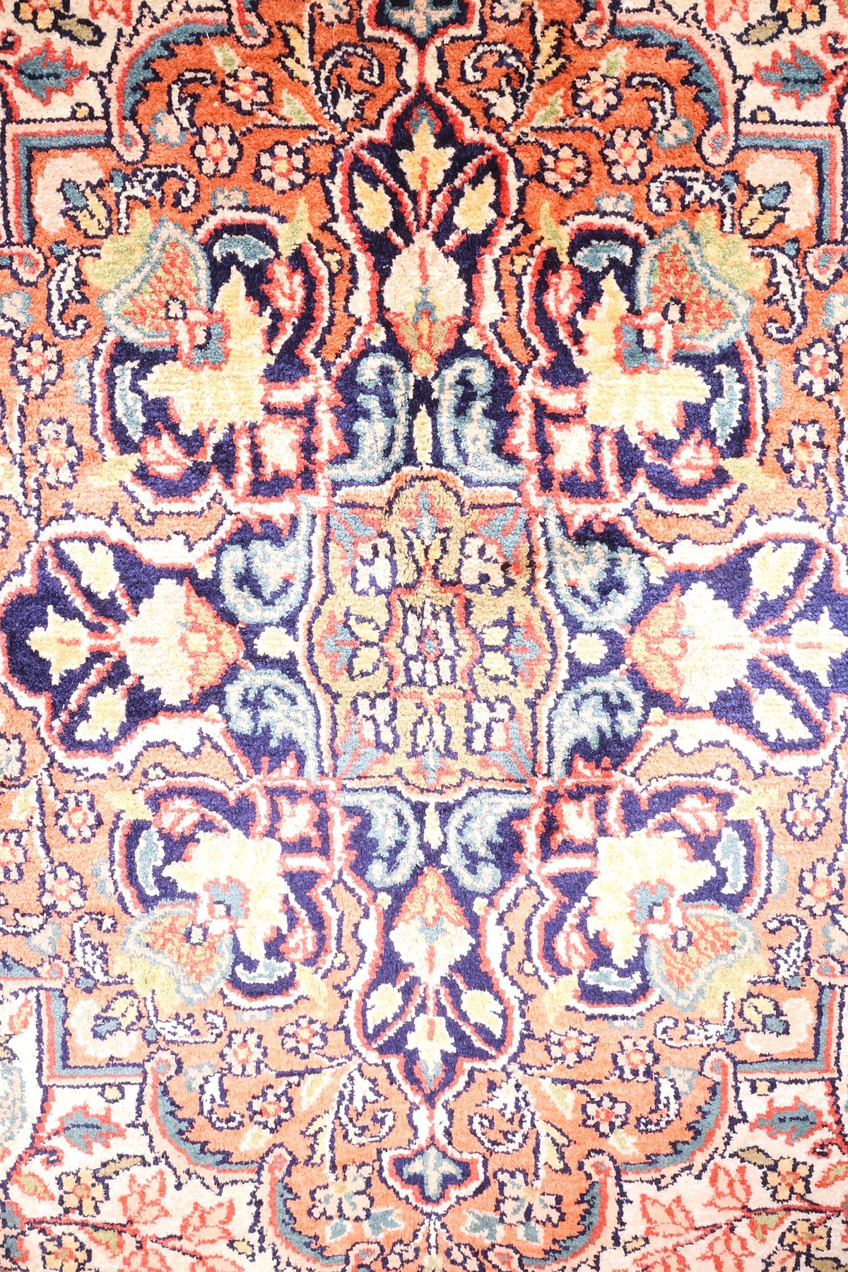 Détail du médaillon bleu nuit et des rinceaux fleuris du tapis Cachemire orange