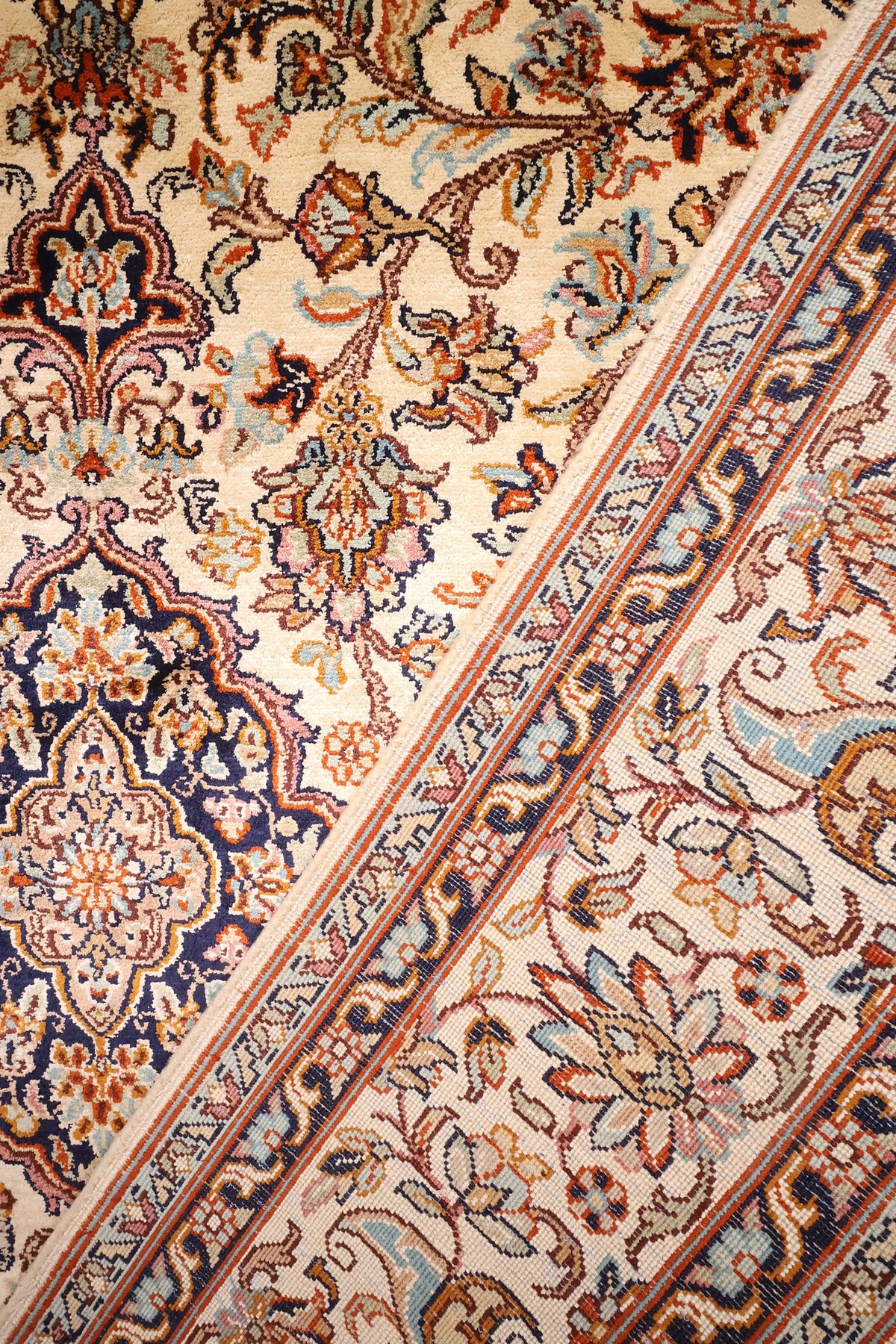 Coin replié du tapis Cachemire en soie, envers et bordure florale côte à côte