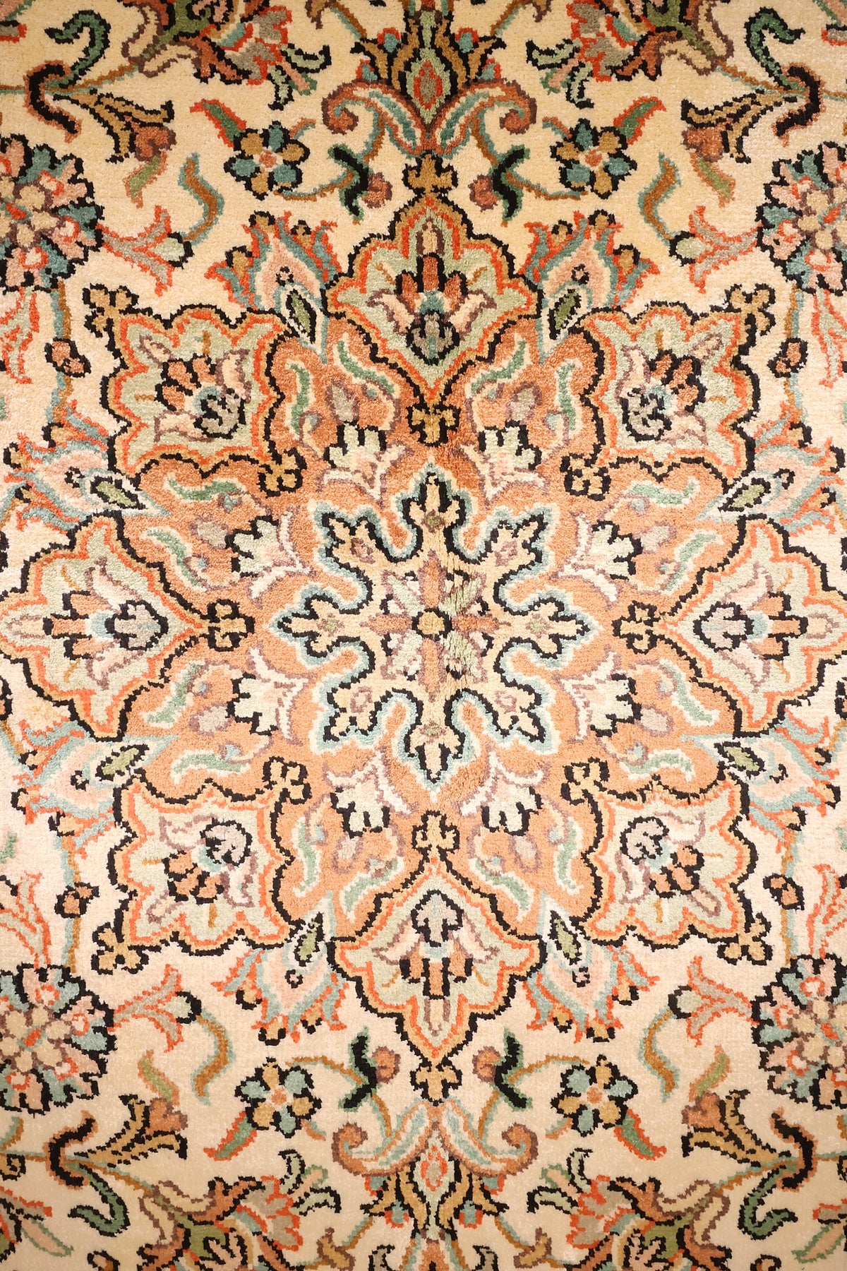 Détail du médaillon saumon et des rinceaux fleuris du tapis Cachemire beige
