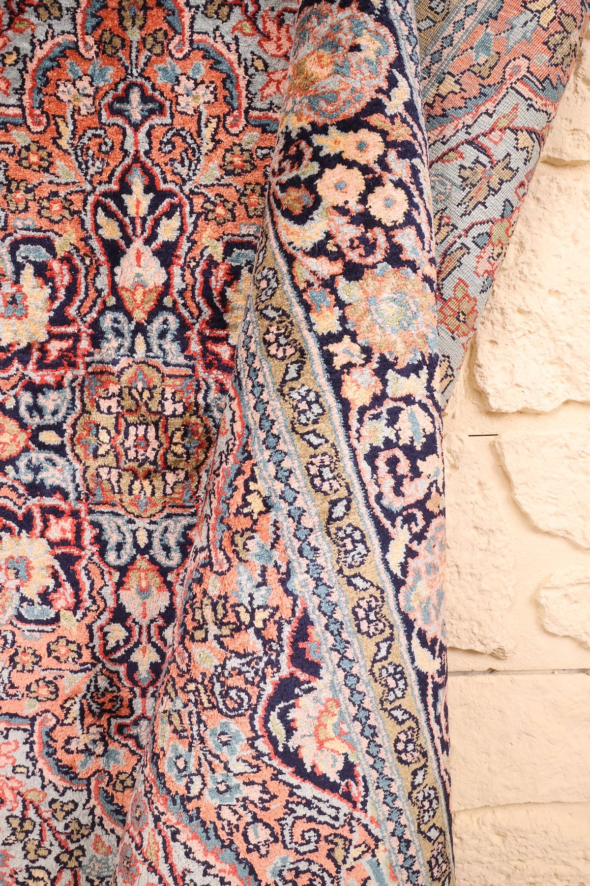 Tapis Cachemire rose et bleu, pan replié sur les rinceaux fleuris de la bordure