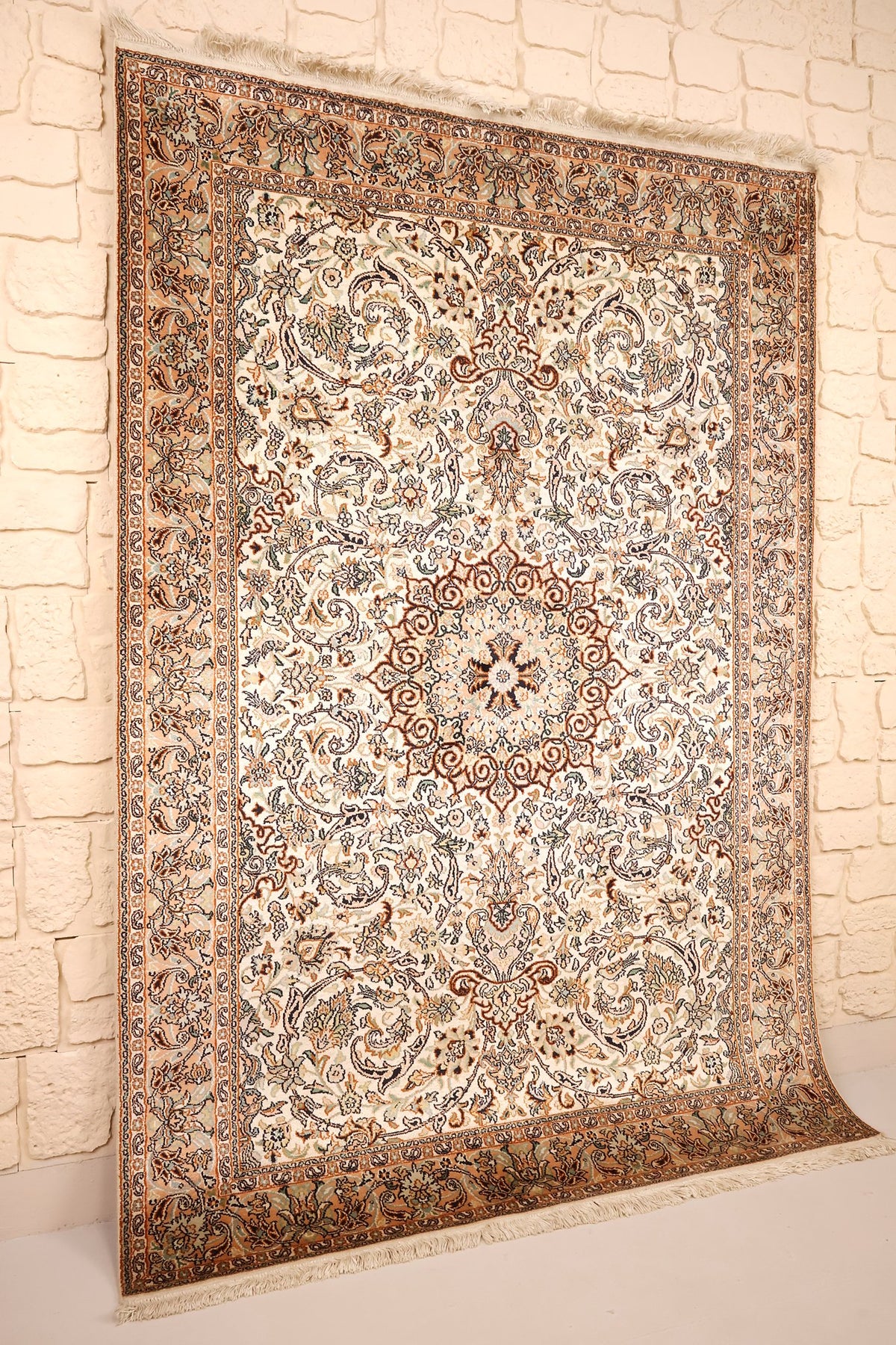 Tapis Cachemire en soie noué à la main, vue de biais contre un mur clair