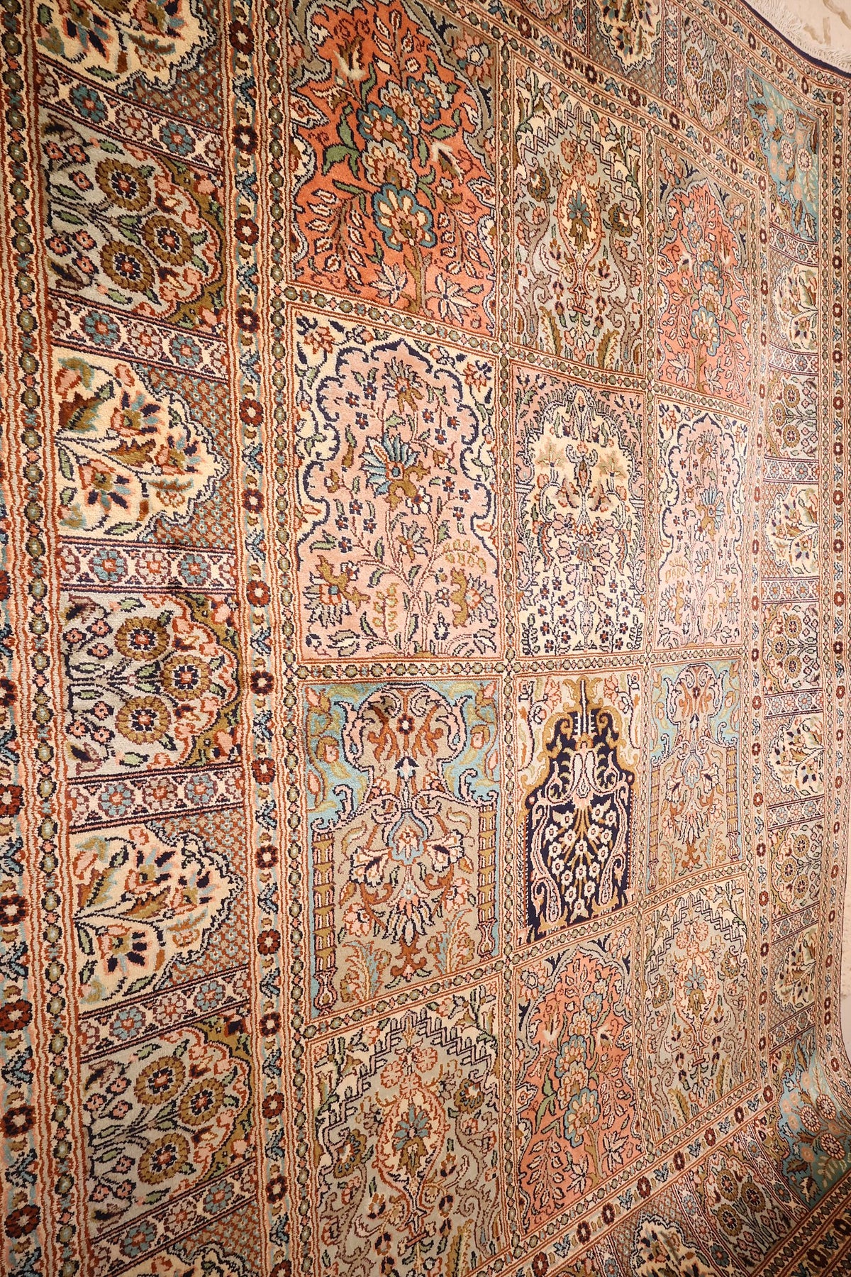 Vue inclinée du tapis Cachemire beige, cases fleuries et panneau bleu nuit