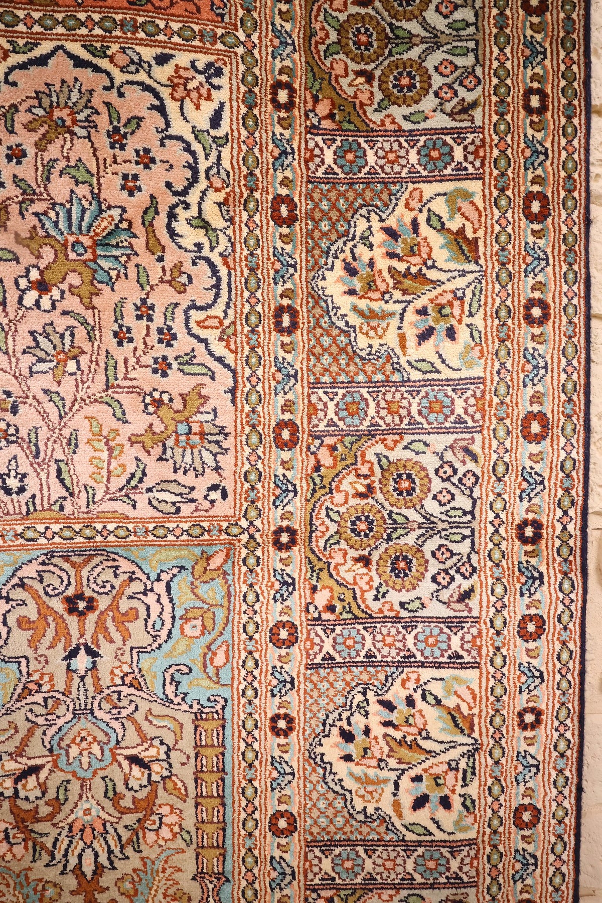 Détail du tapis Cachemire : case saumon et bordure ivoire à rosettes