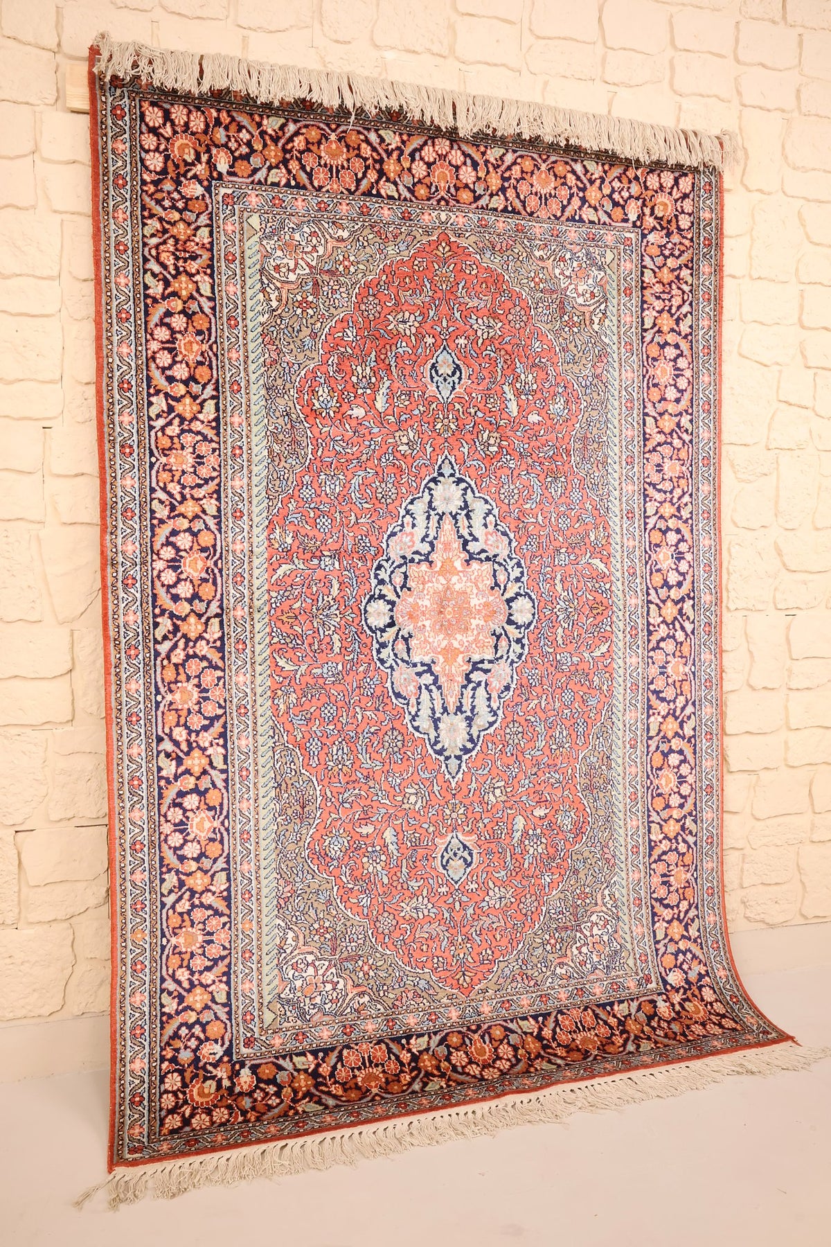 Tapis Cachemire en soie nouée main, vue de biais montrant le champ corail et les franges ivoire