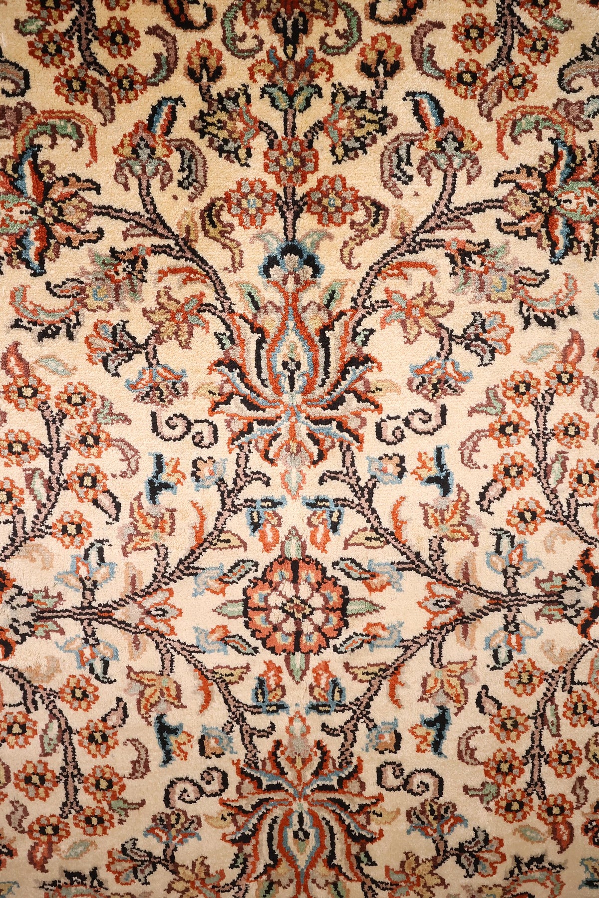 Détail des rinceaux fleuris orange, rose et bleu sur champ beige ivoire