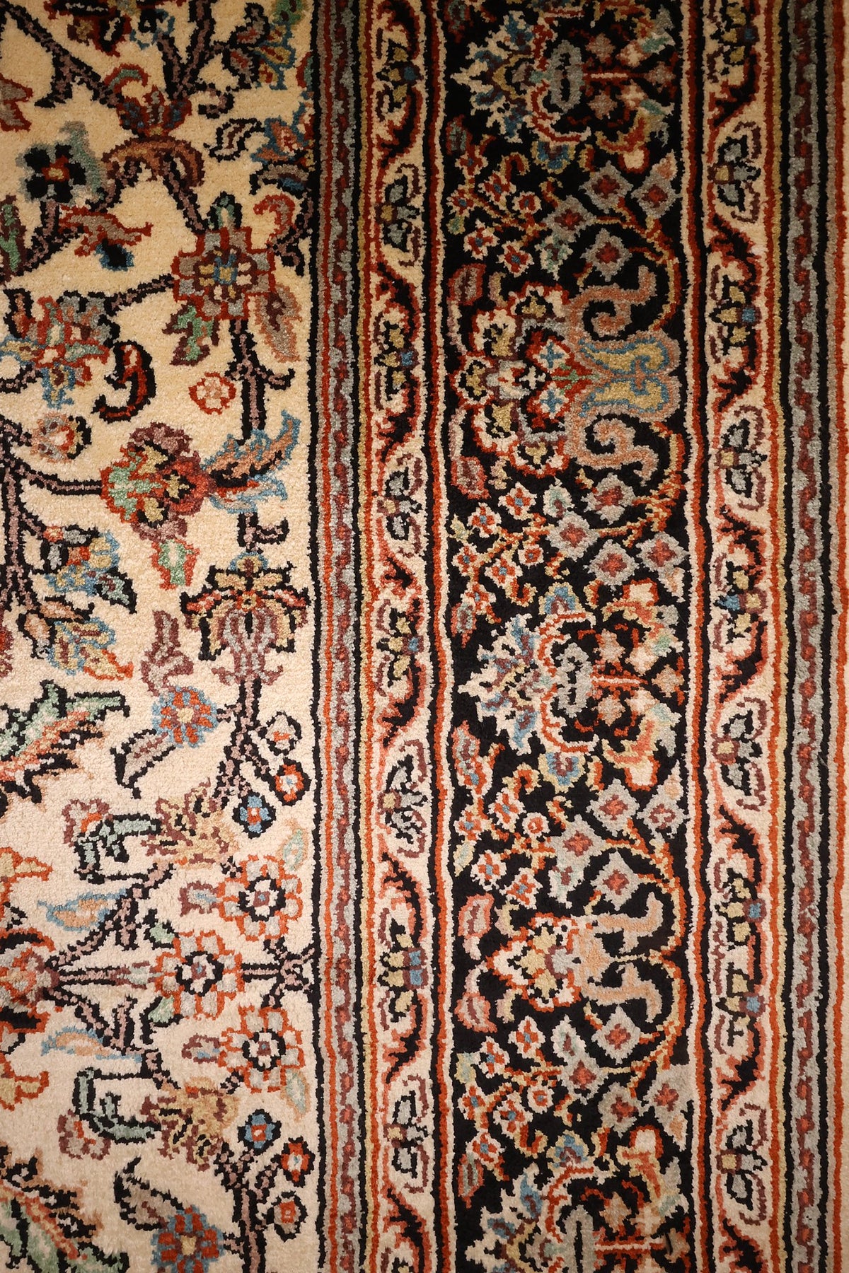 Bordure noire à palmettes et contre-bordures à filets orange du tapis Cachemire