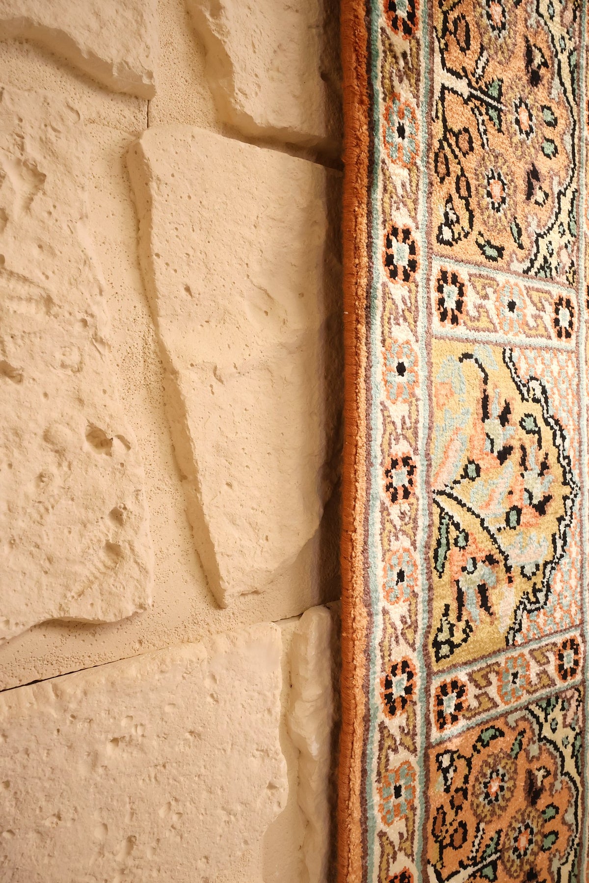 Lisière du tapis Cachemire beige et orange, bord noué net le long du mur