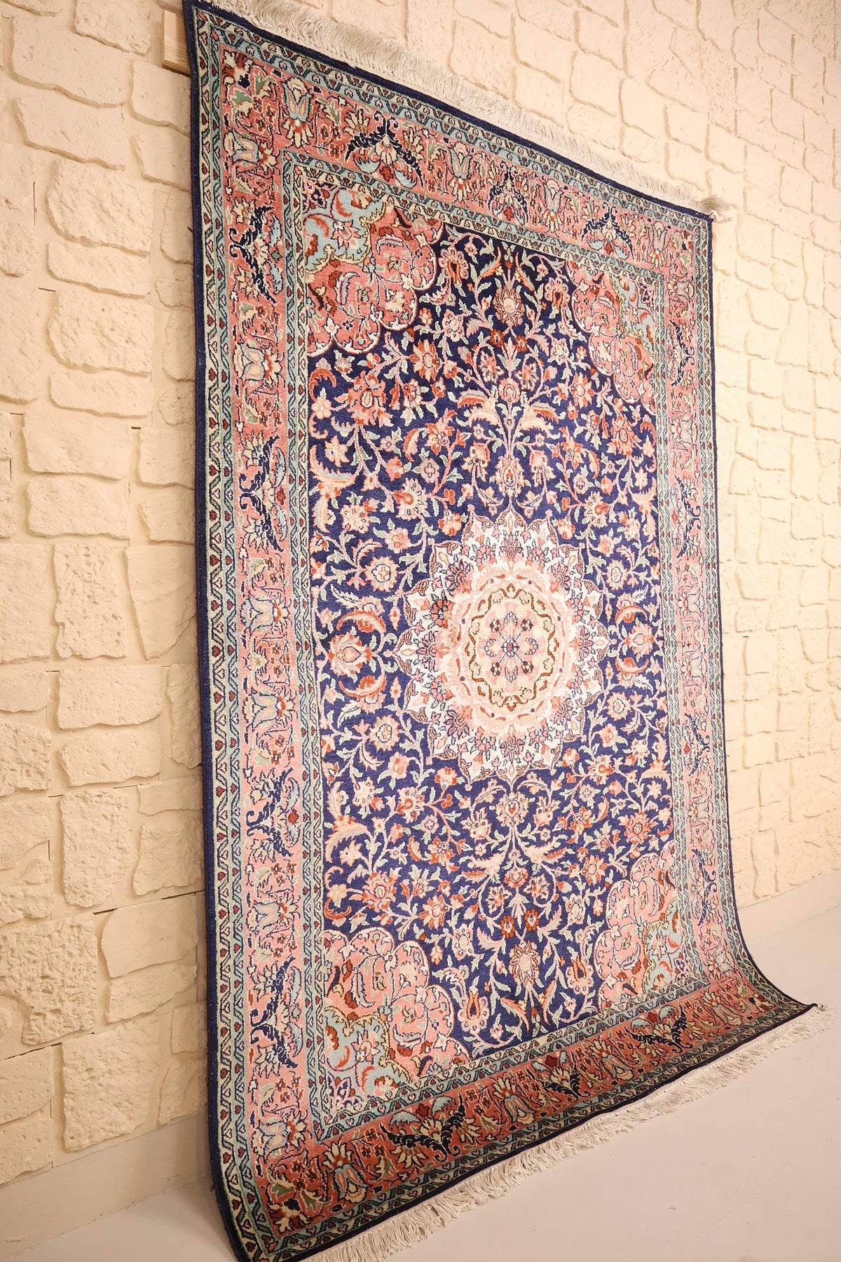 Tapis Cachemire en soie bleu nuit vu de biais, champ fleuri et bordure rose saumon
