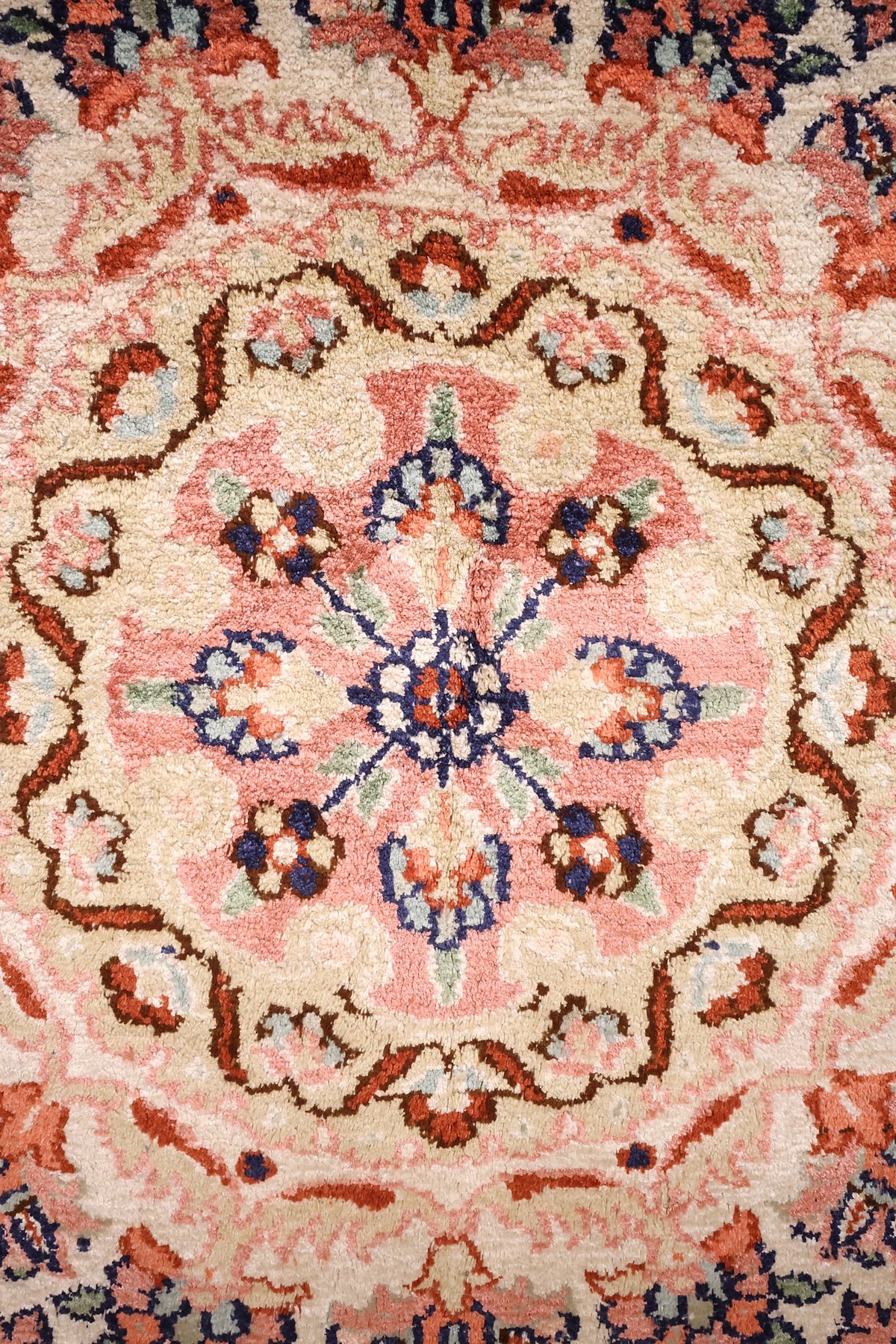 Détail du médaillon rond rose et ivoire à contour dentelé du tapis Cachemire