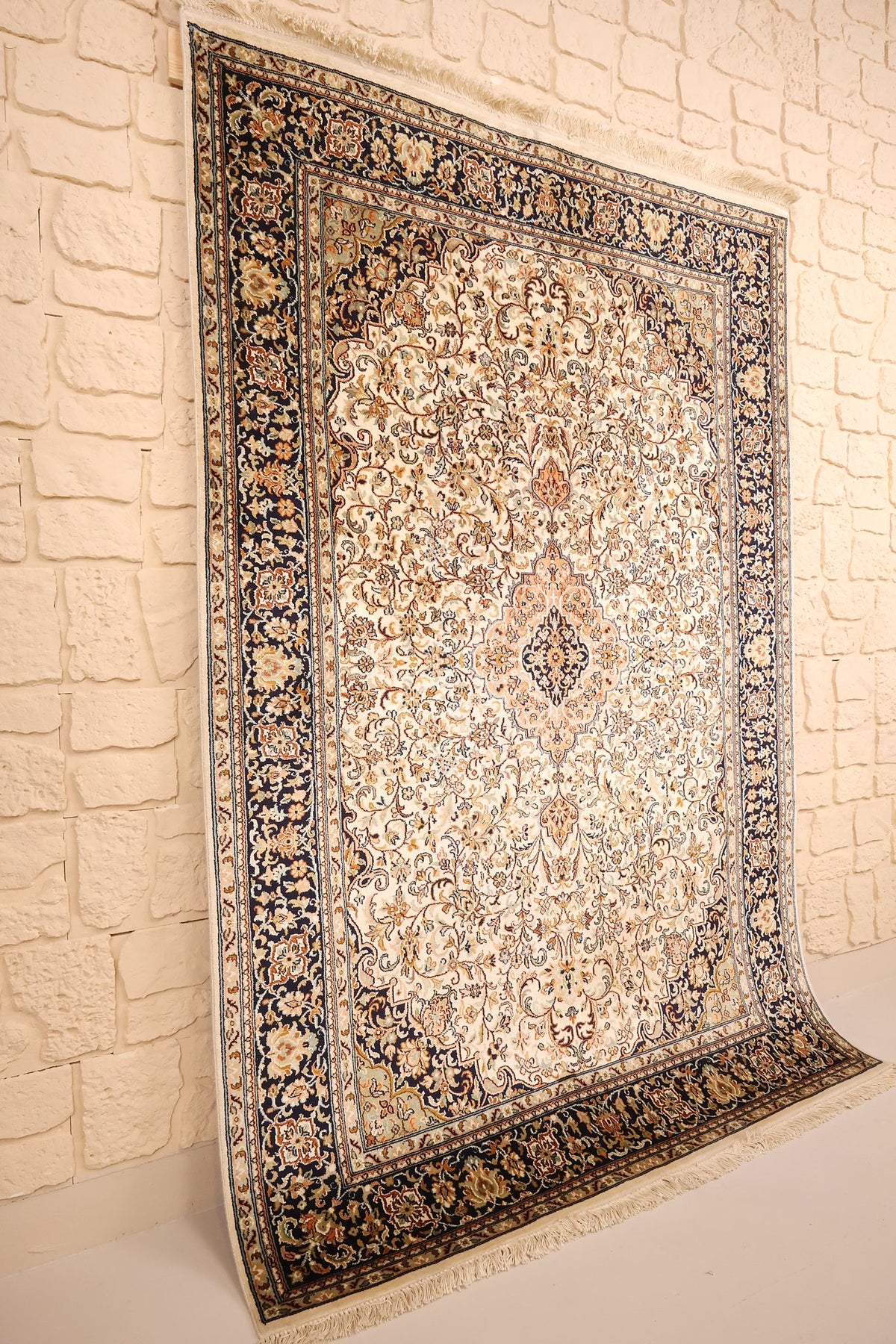 Tapis Cachemire beige et bleu nuit vu de biais, champ fleuri et bordure sombre