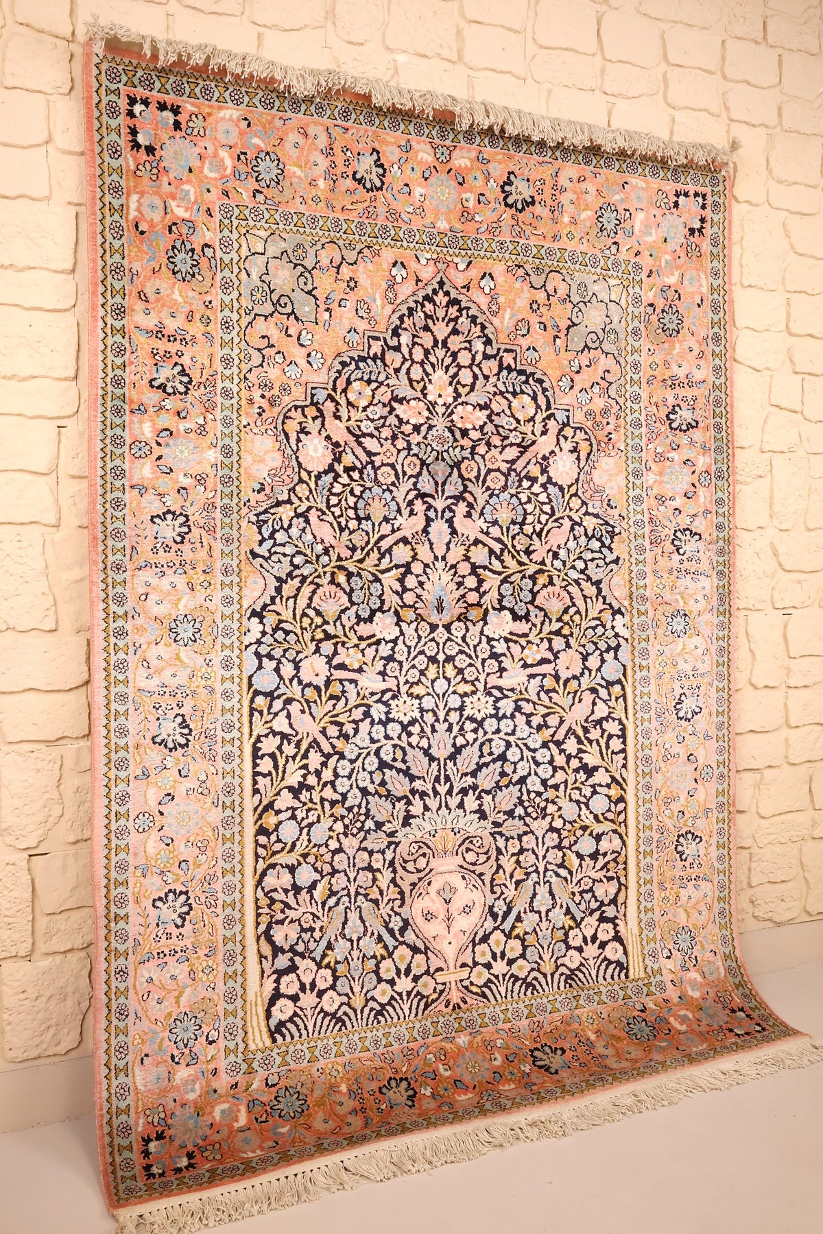 Vue de biais du tapis Cachemire en soie, champ bleu nuit et bordure rose saumon