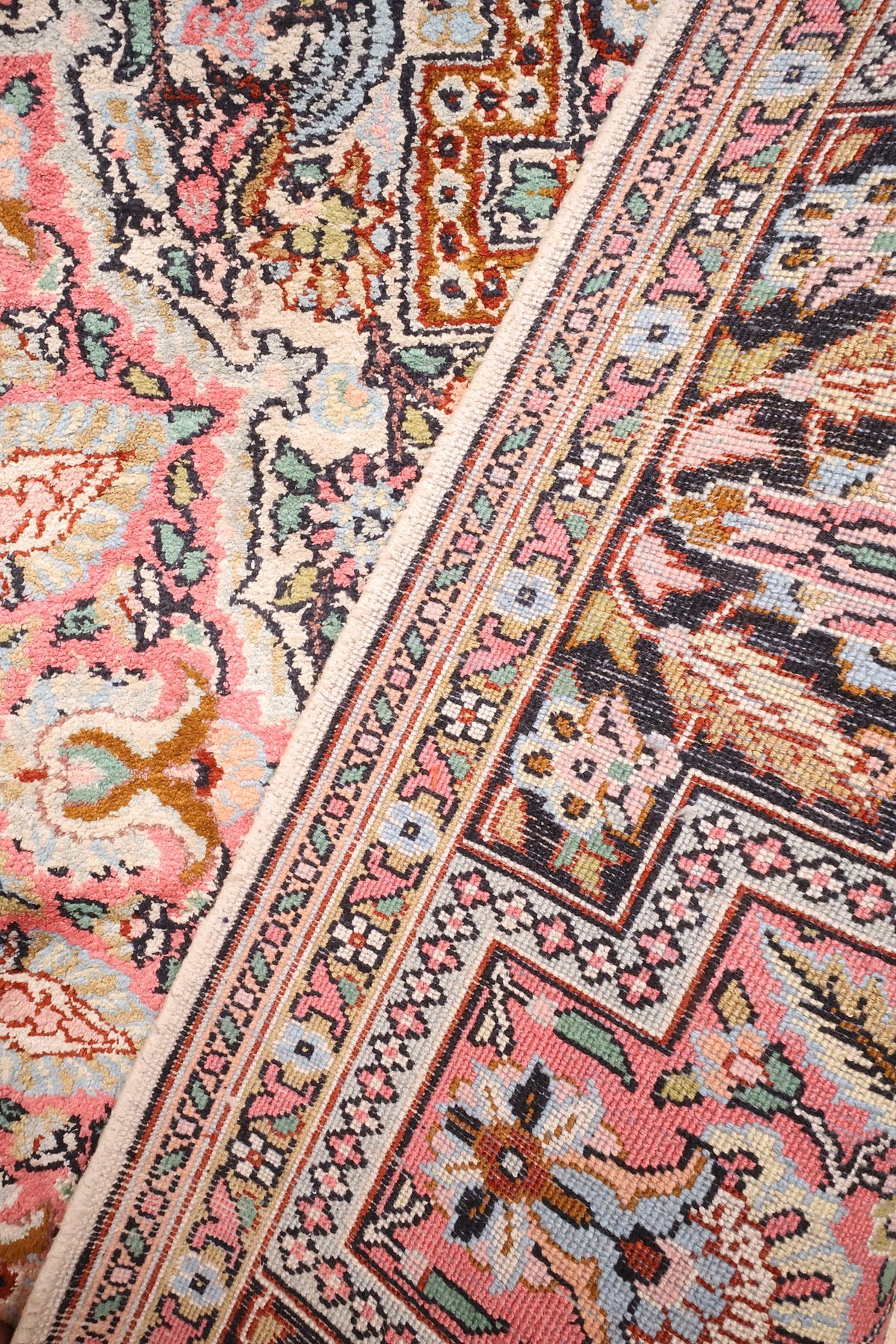 Coin replié du tapis Cachemire en soie, rinceaux fleuris et bordure rose