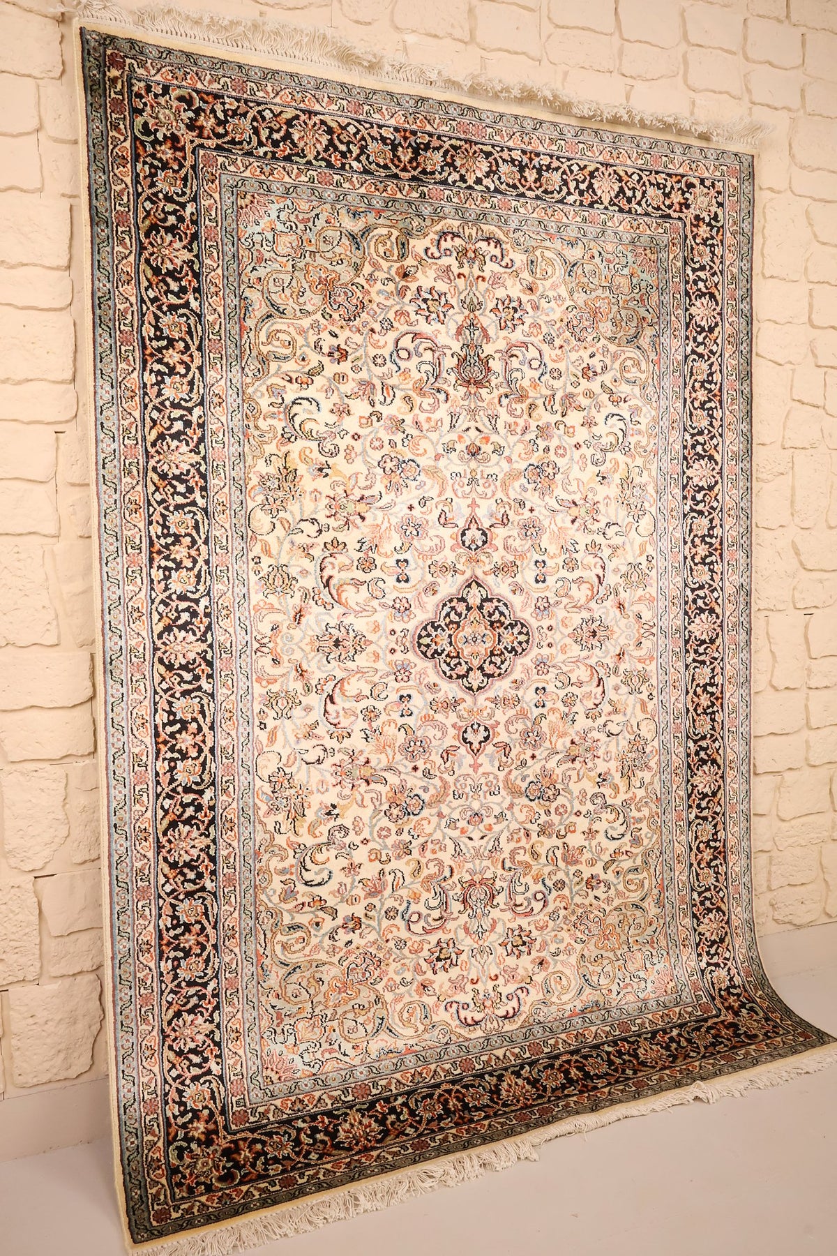 Tapis Cachemire beige et rose vu de biais, bordure bleu nuit et franges blanches