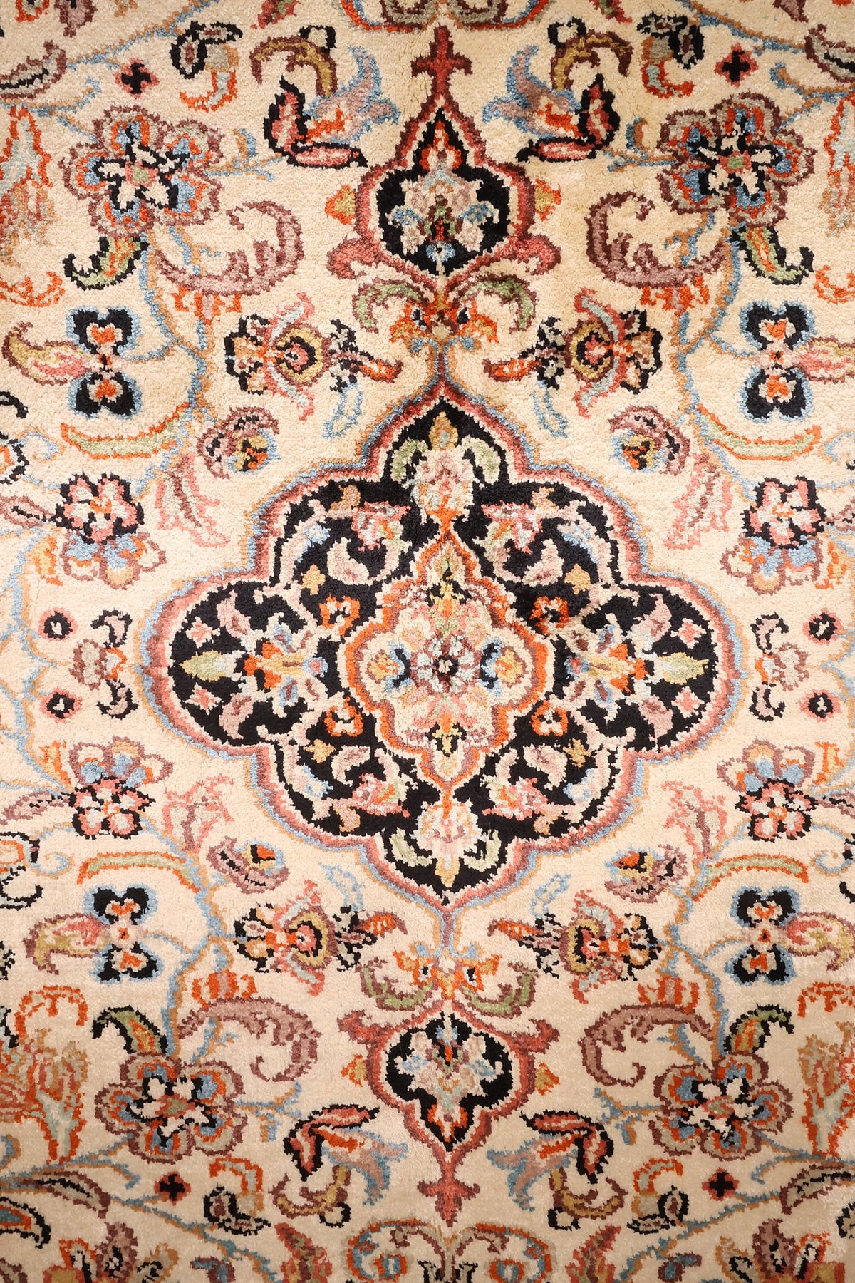 Détail du médaillon lobé et des rinceaux fleuris du tapis Cachemire beige
