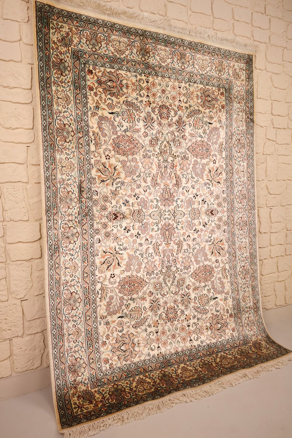 Vue de biais du tapis Cachemire beige, bordures multiples et franges claires