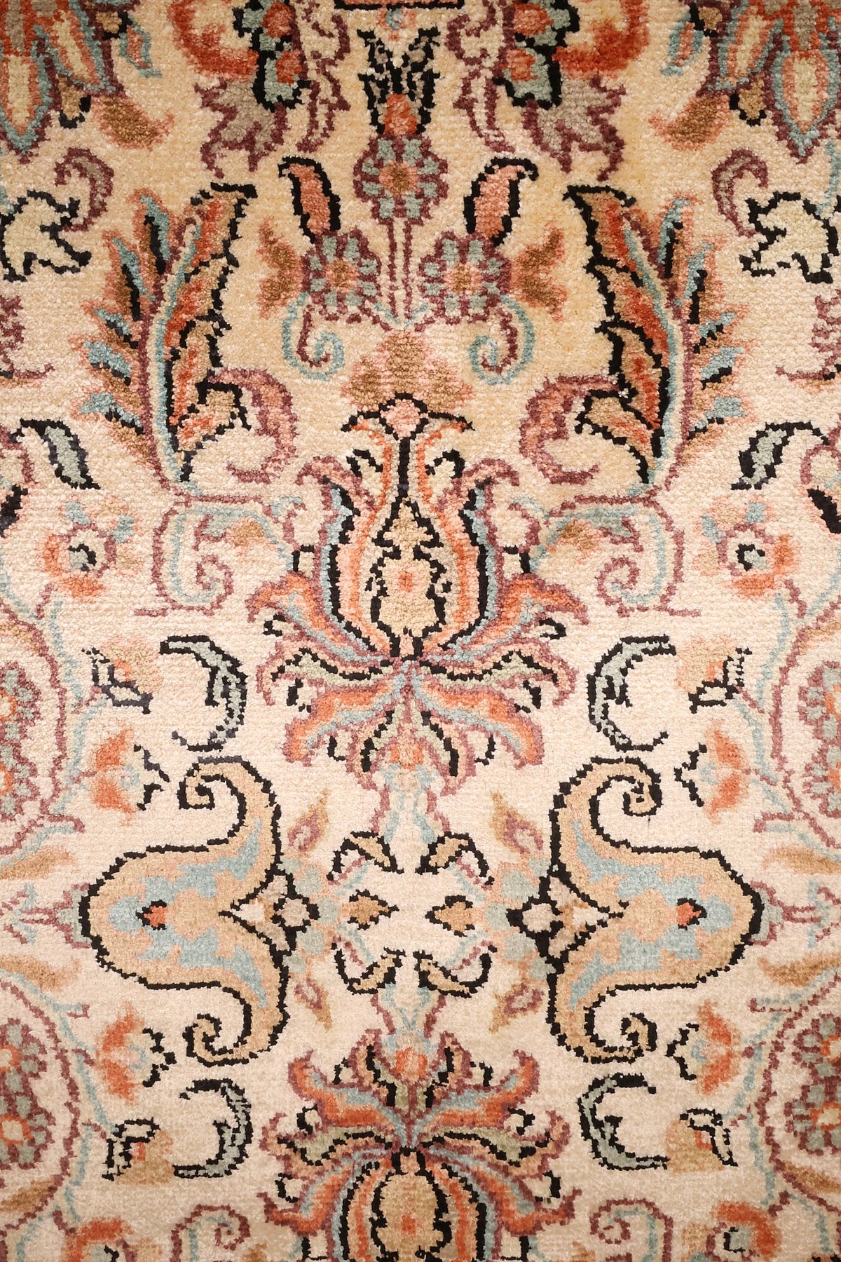Détail des palmettes rose et vert d'eau sur champ ivoire du tapis Cachemire