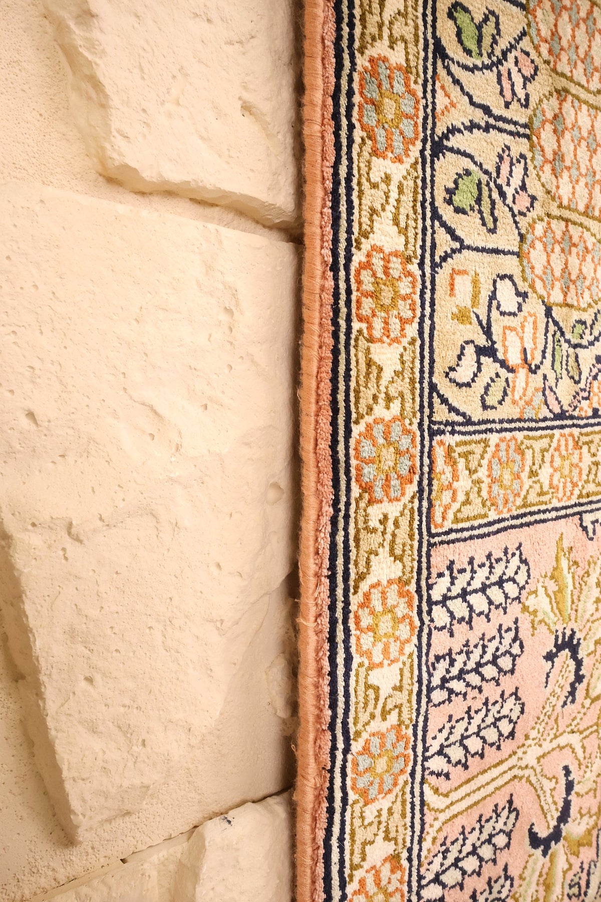 Lisière du tapis Cachemire 186 × 125 cm, bordure fleurie contre un mur clair