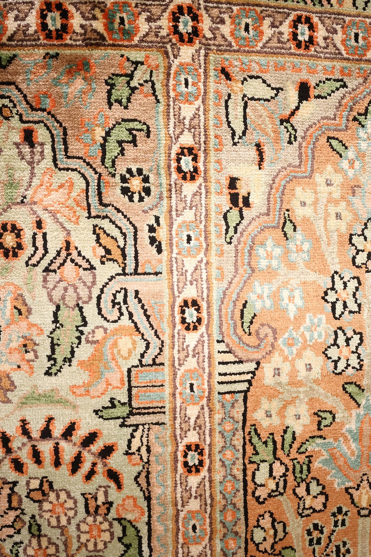 Détail des arcades et rinceaux fleuris verts et orange du tapis Cachemire