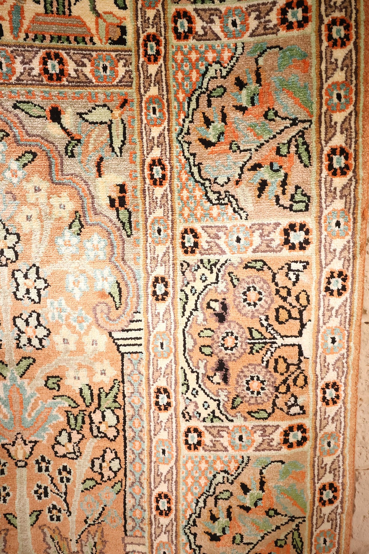 Bordure ivoire à rosettes orange encadrant le champ beige du tapis Cachemire