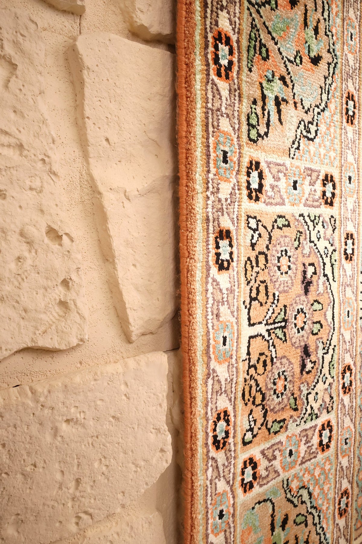 Lisière du tapis Cachemire en soie, bande orangée et petites rosettes noires