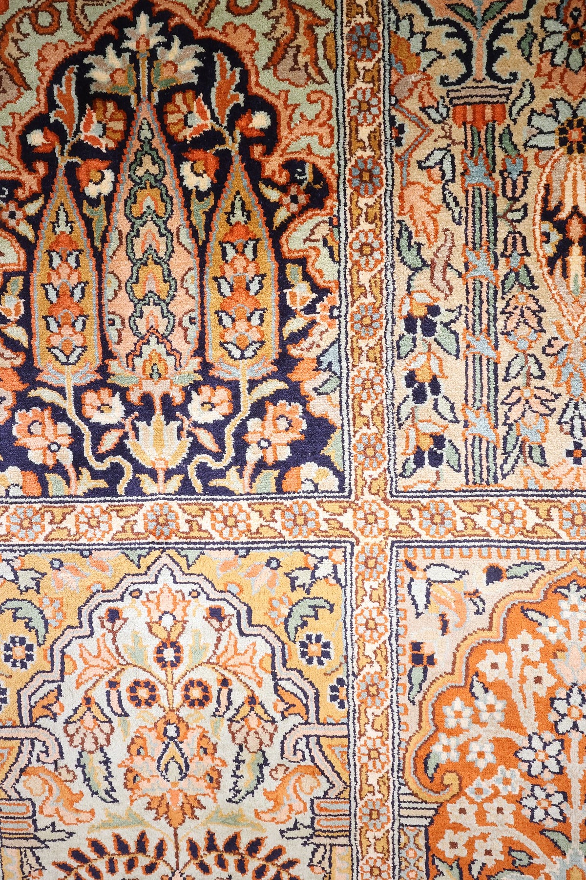 Détail des arbres fleuris sur fond bleu nuit et orange du tapis Cachemire