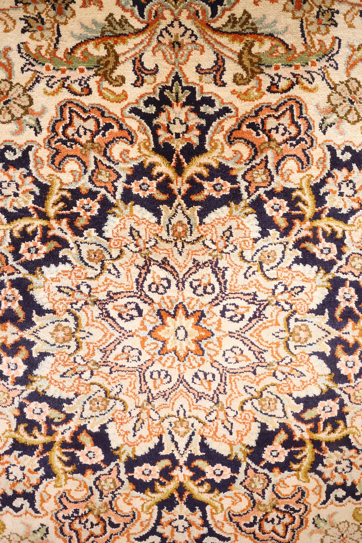 Détail du médaillon étoilé orange sur fond bleu nuit du tapis Cachemire
