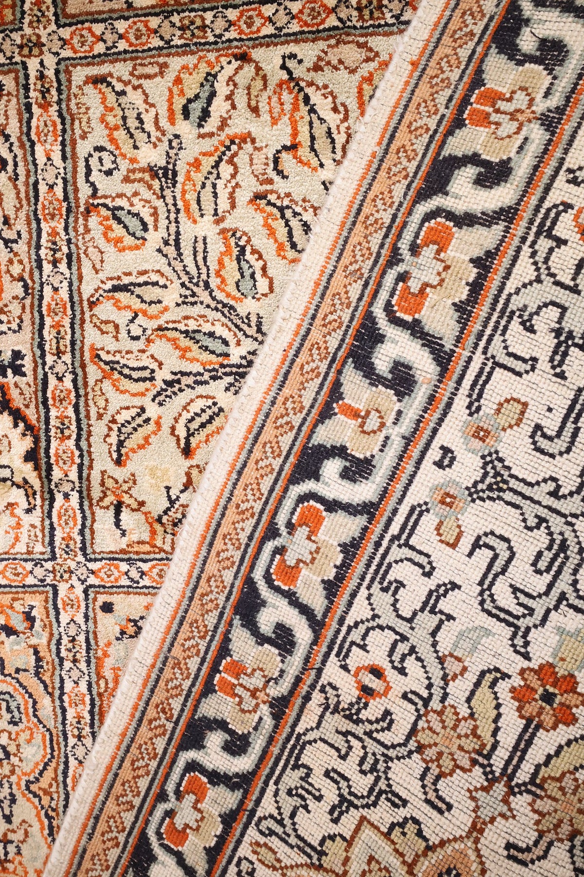 Coin replié du tapis Cachemire, contre-bordures sombres à volutes et finesse de la soie