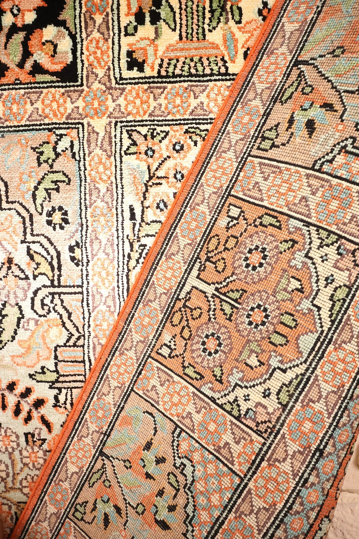 Coin replié du tapis Cachemire orange, caissons et bordure claire côte à côte