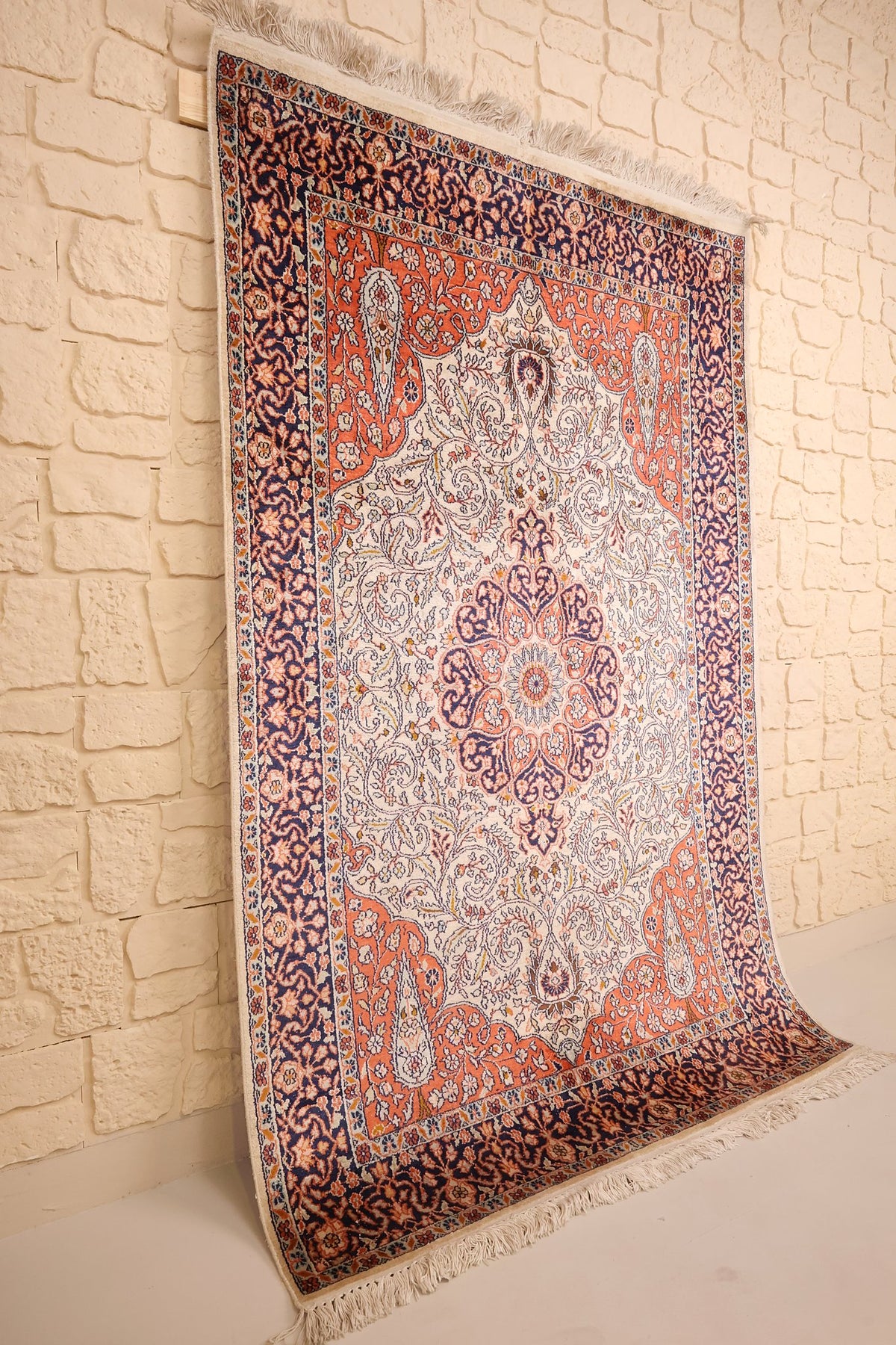 Tapis Cachemire beige et orange vu de biais, médaillon central et écoinçons visibles