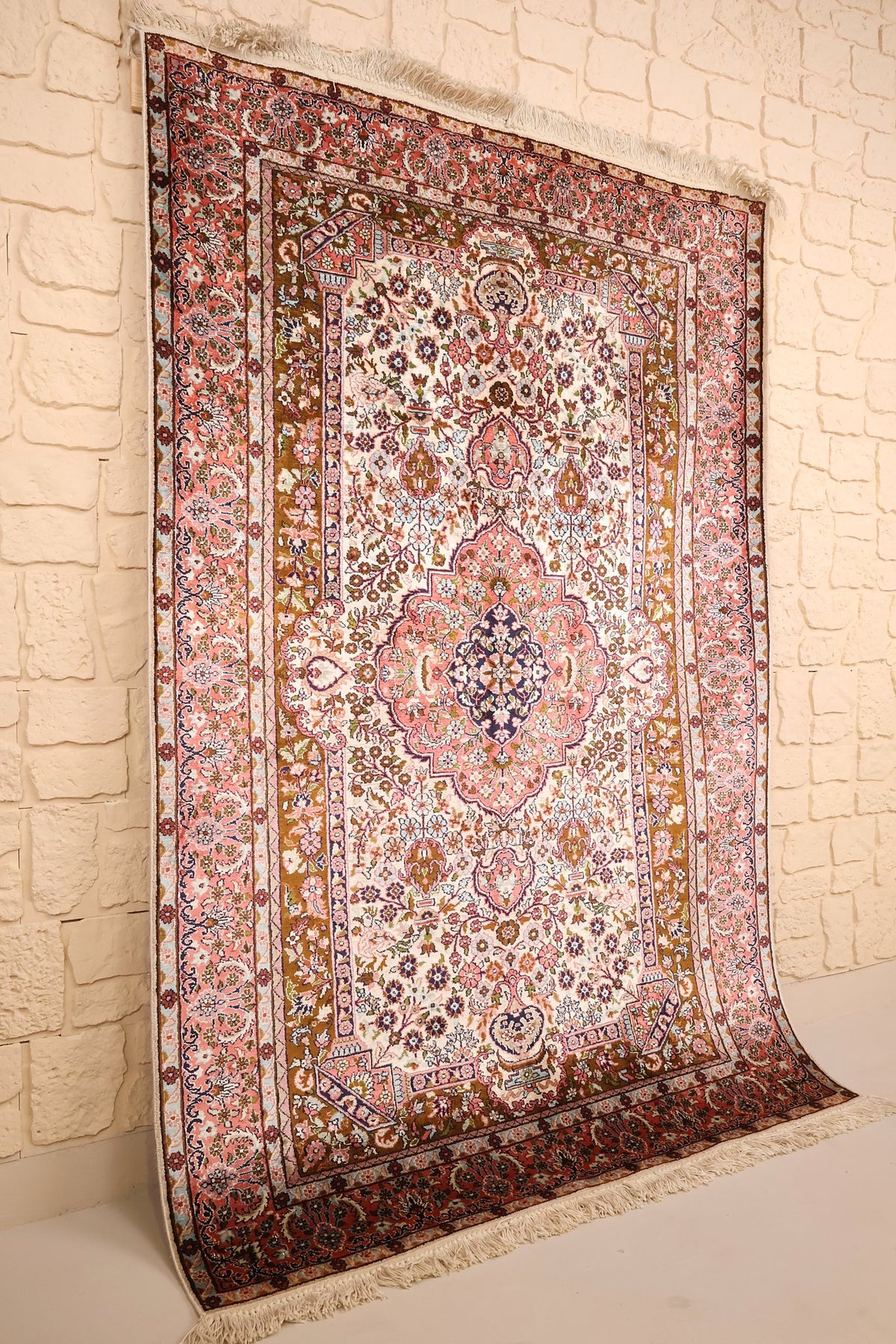 Tapis Cachemire rose et beige vu de biais, champ ivoire fleuri et bordures roses