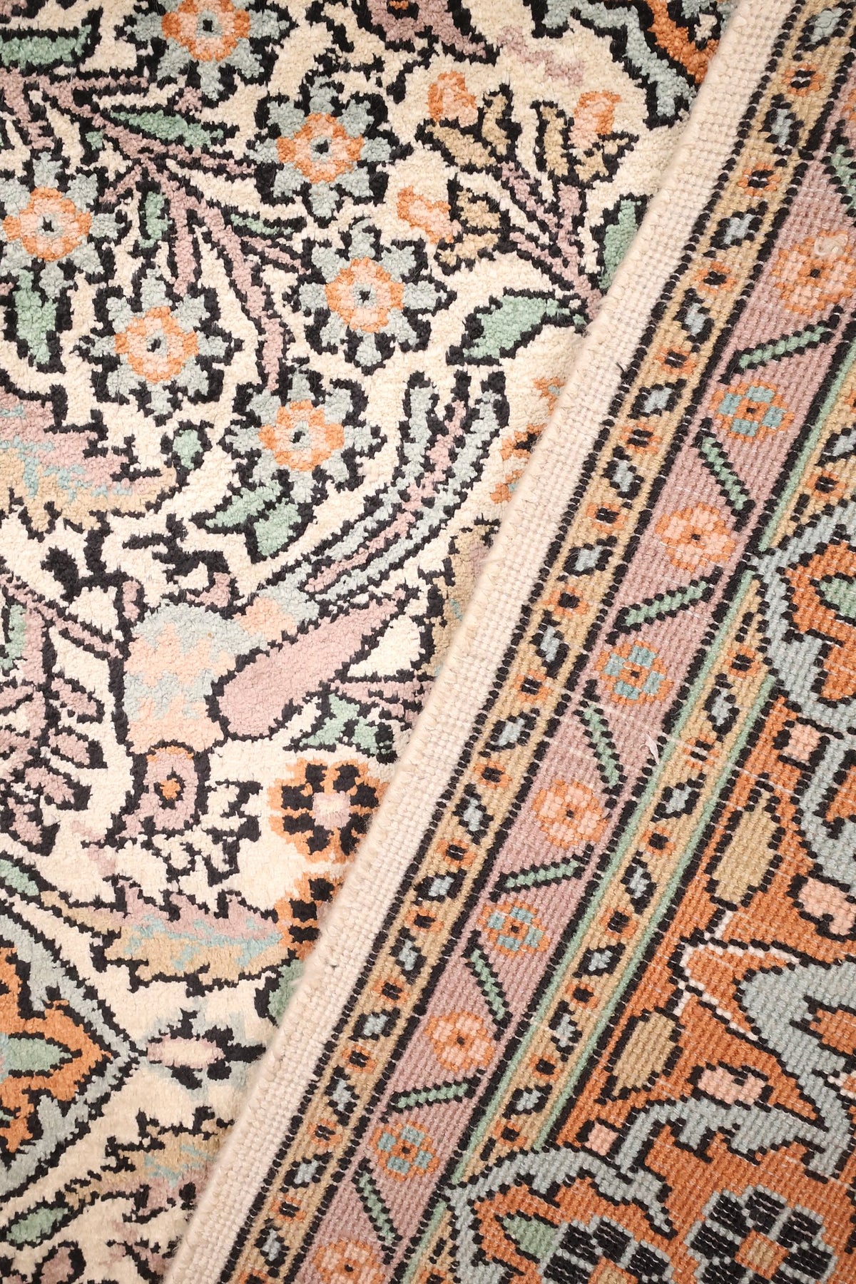 Coin du tapis Cachemire noué main, rosettes et contours noirs sur fond ivoire