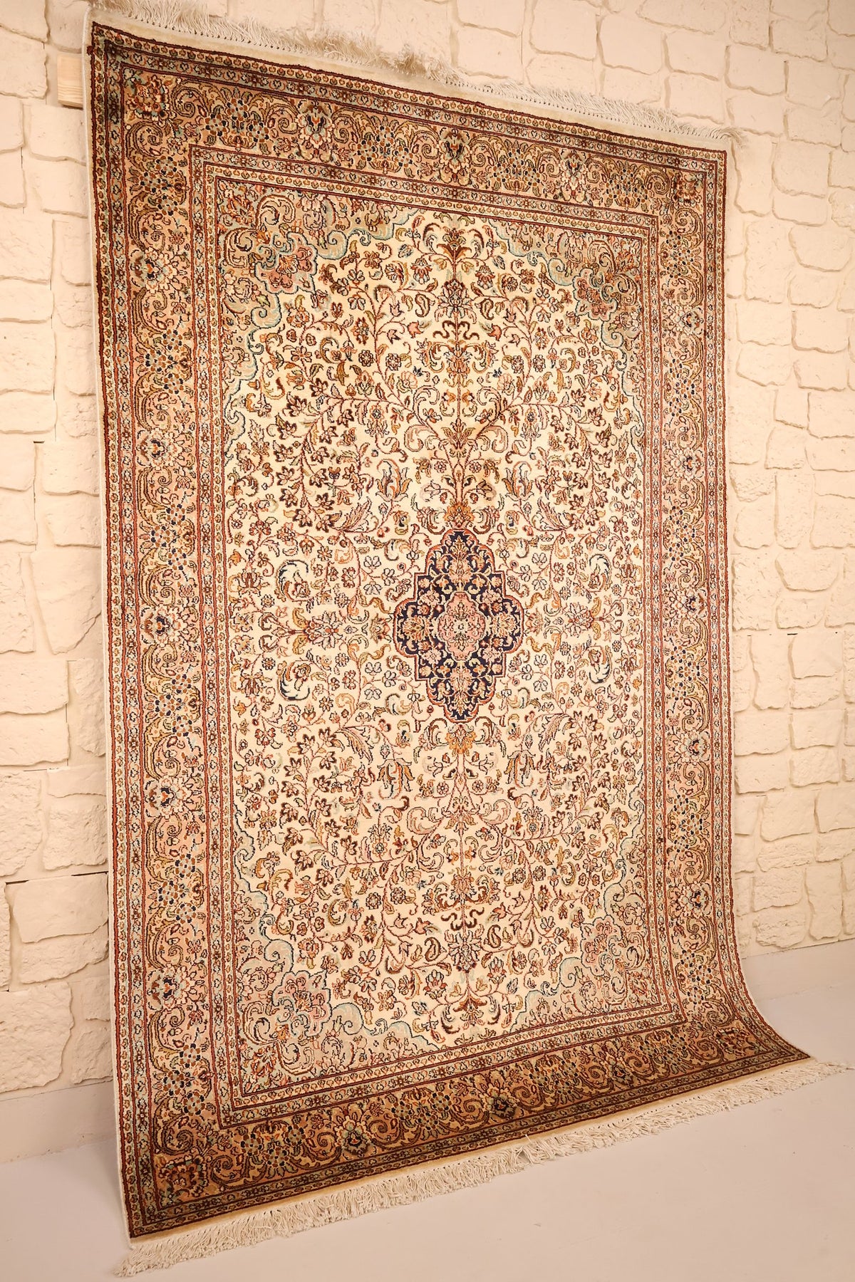 Tapis Cachemire en soie beige et orange, vue de biais montrant le champ fleuri et les franges