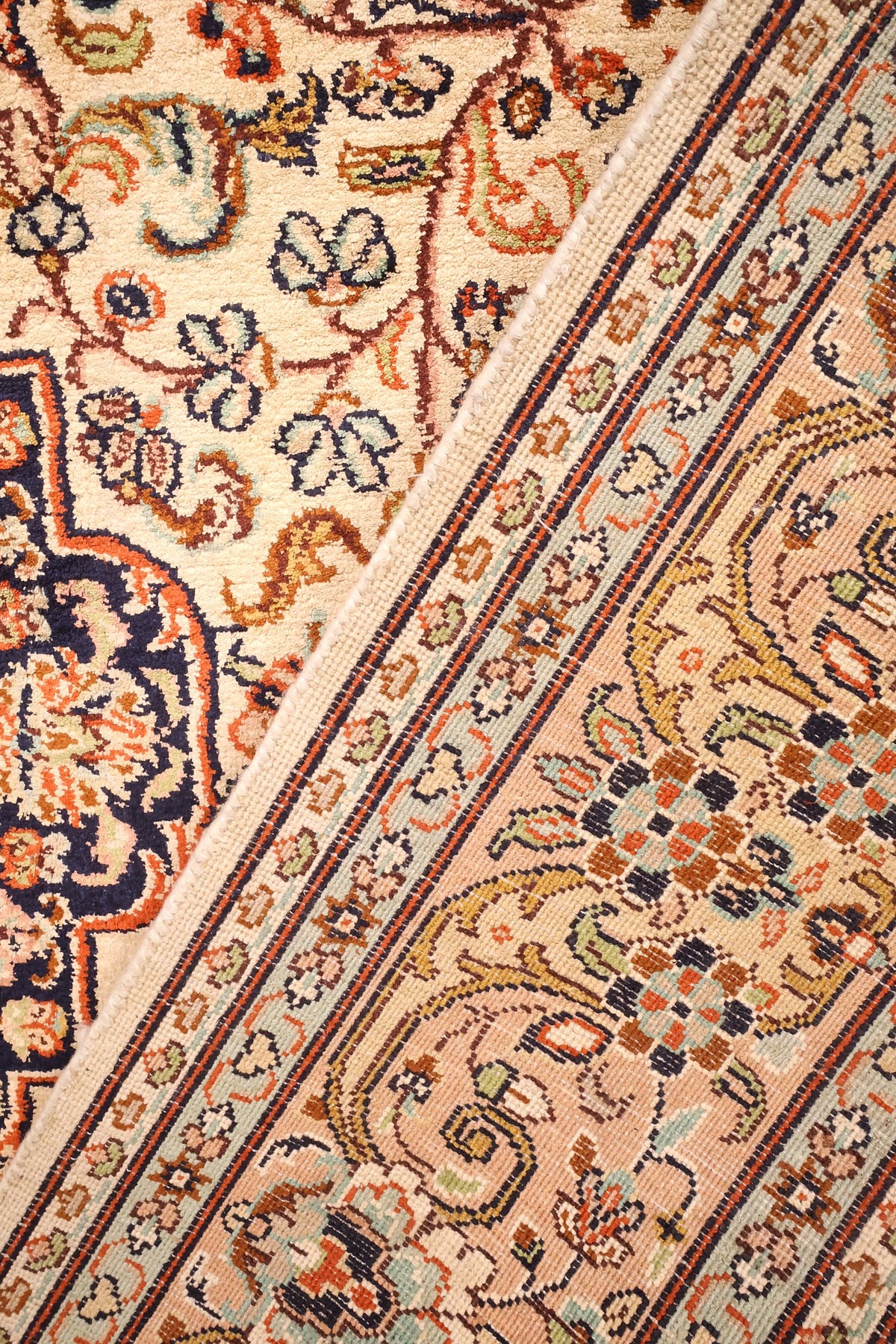 Coin replié du tapis Cachemire, envers noué main et bordure fleurie côte à côte