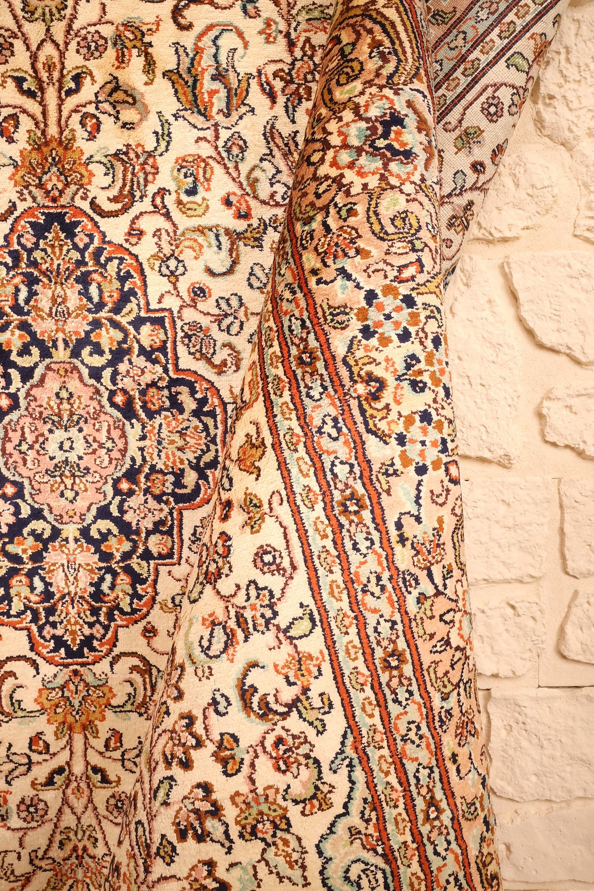 Pli du tapis Cachemire en soie, rinceaux fleuris et filets orange de la bordure