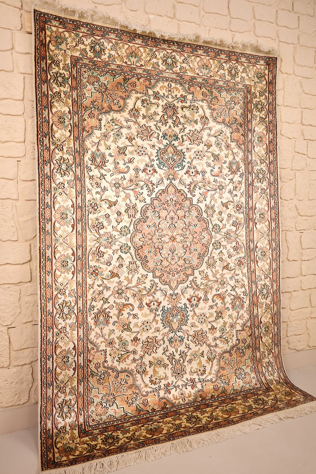 Tapis Cachemire en soie nouée main, vue de biais montrant le champ ivoire fleuri