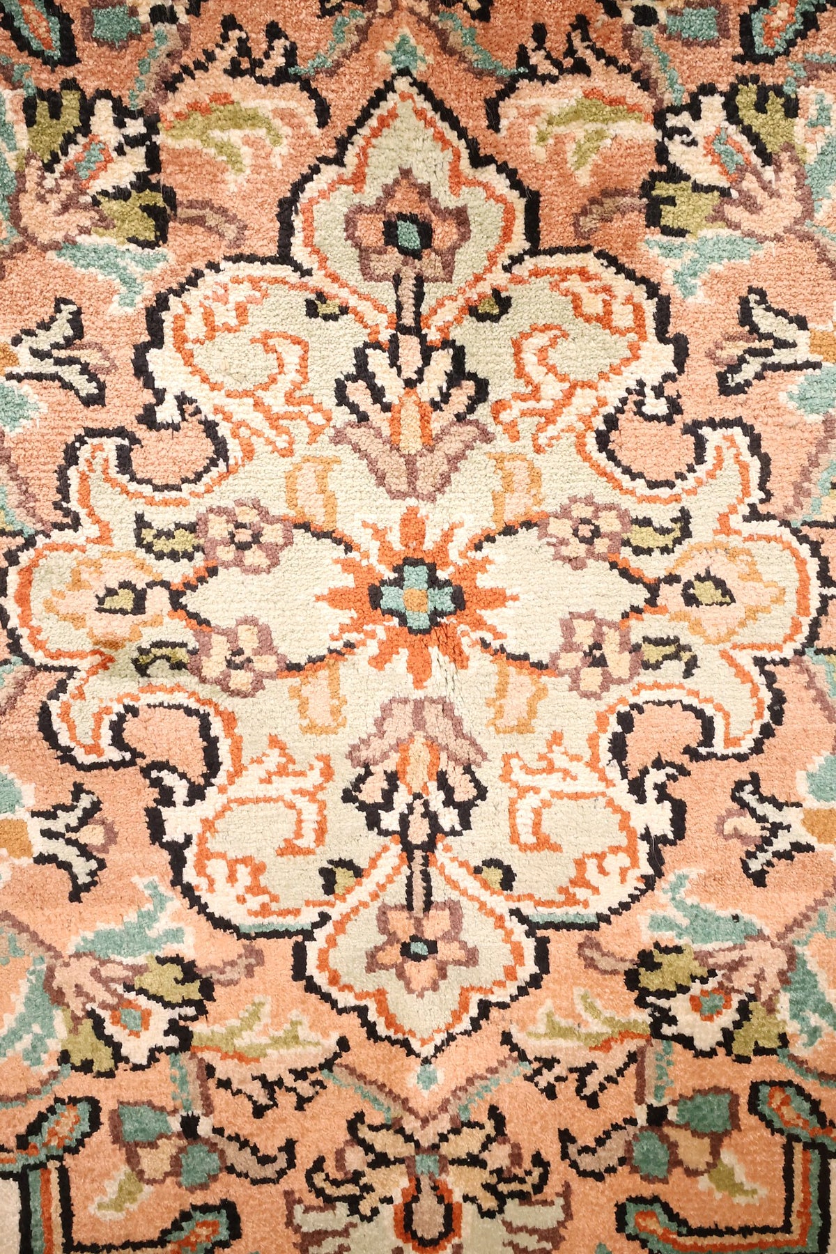 Détail du médaillon rose saumon à cœur ivoire du tapis Cachemire beige