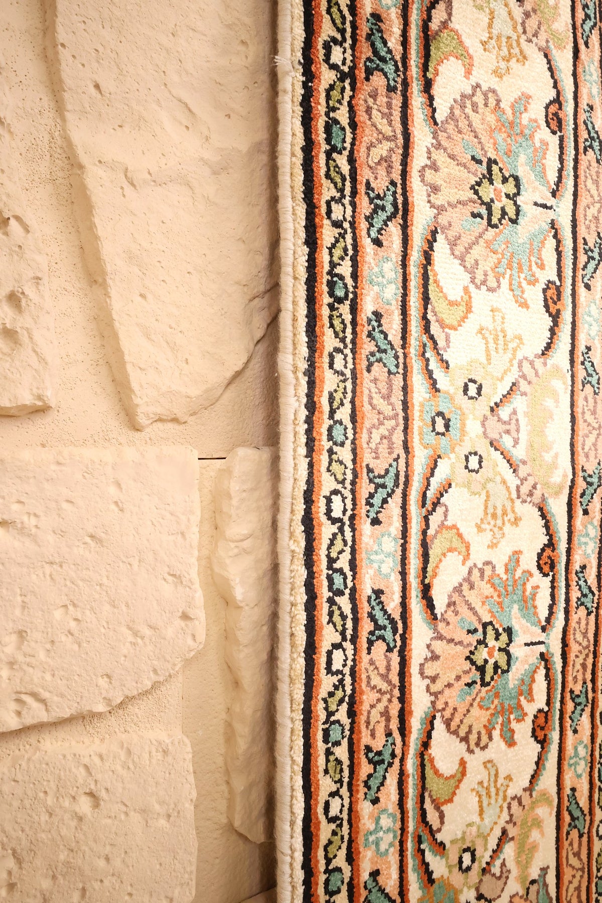 Lisière du tapis Cachemire beige, filets orange et noirs le long du bord
