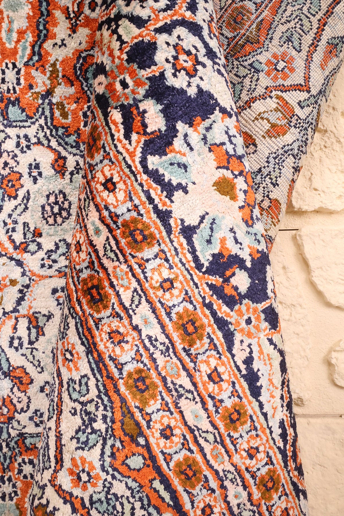 Tapis Cachemire en soie replié, écoinçon orange et bleu vu de près