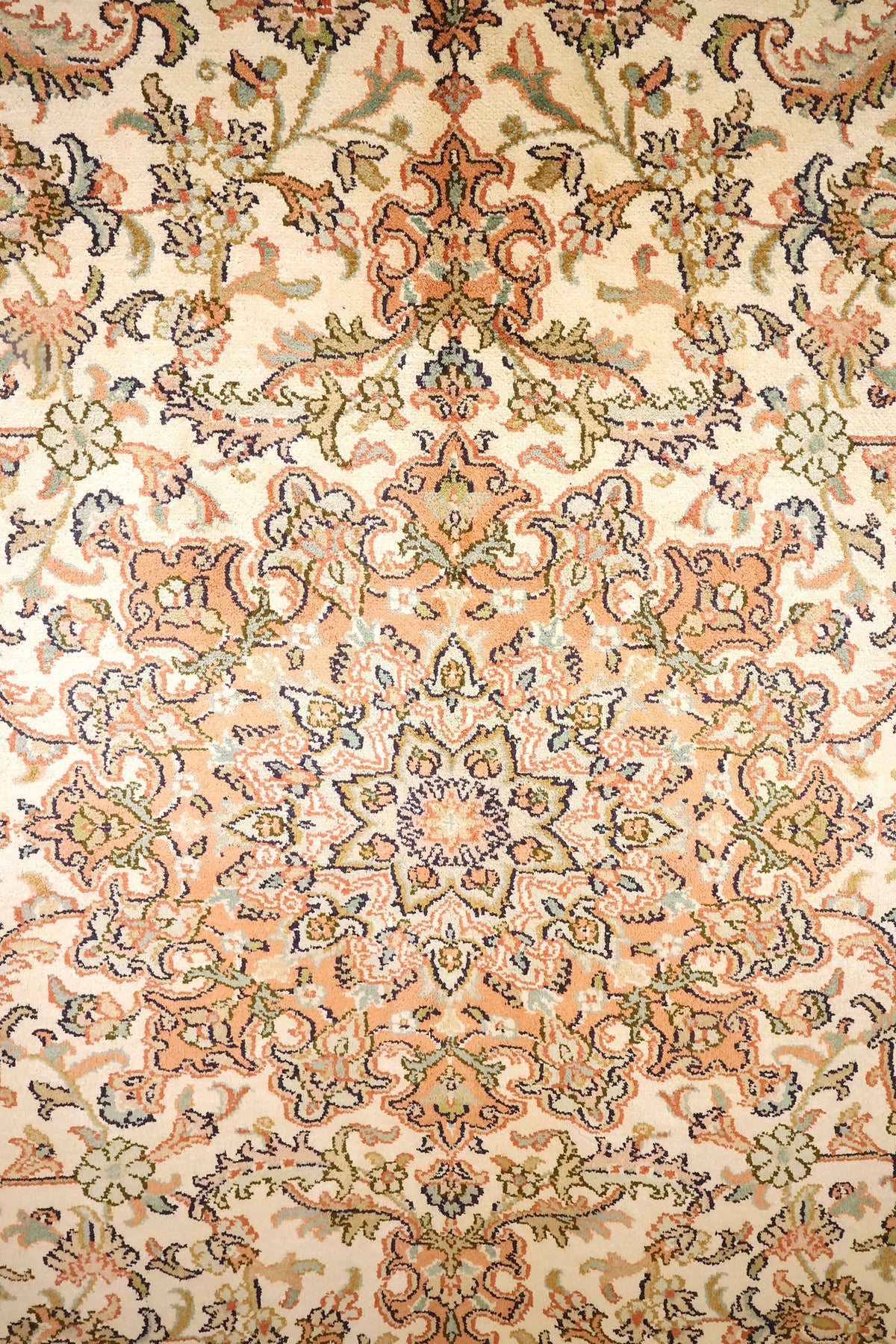 Détail du médaillon en étoile et des rinceaux orange et vert olive du Cachemire beige