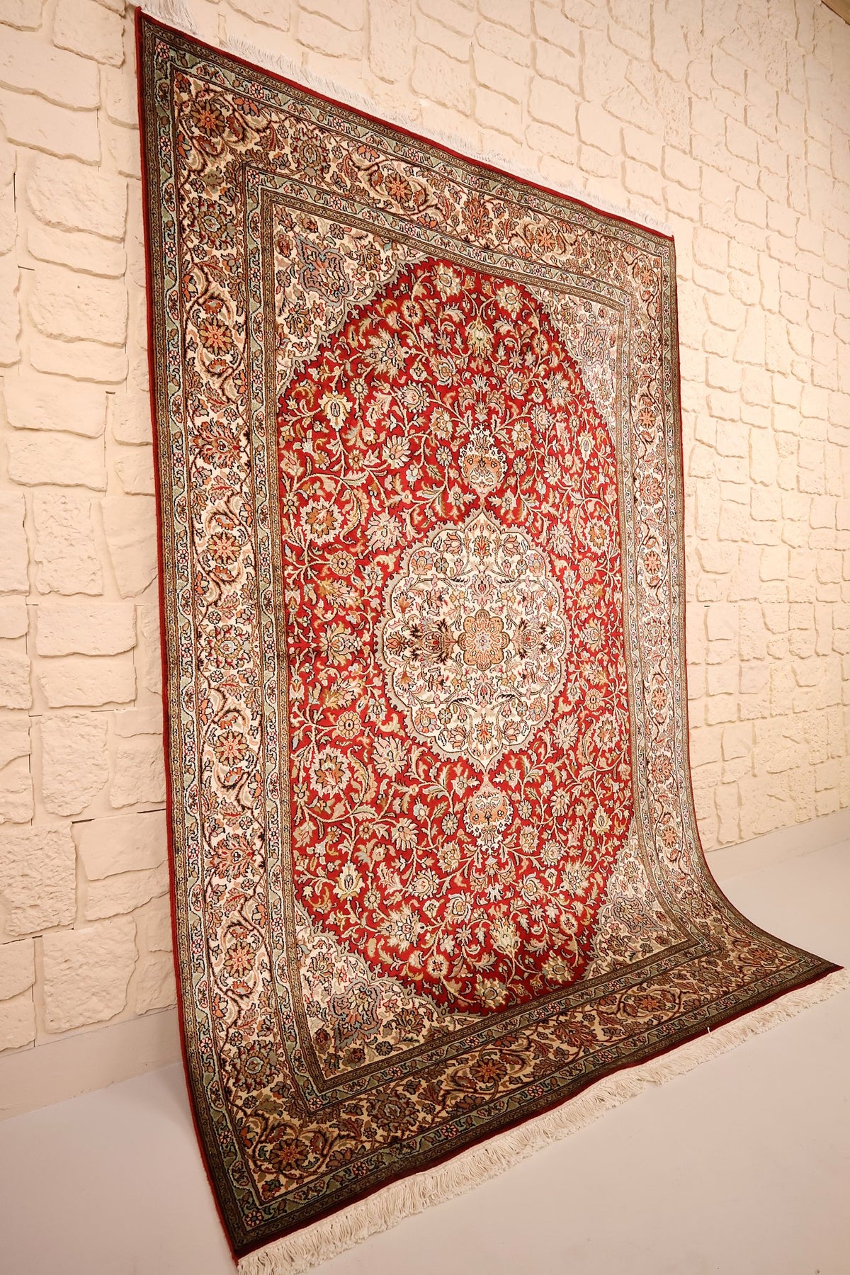 Tapis Cachemire en soie noué à la main, vue de biais du champ rouge et de ses bordures ivoire