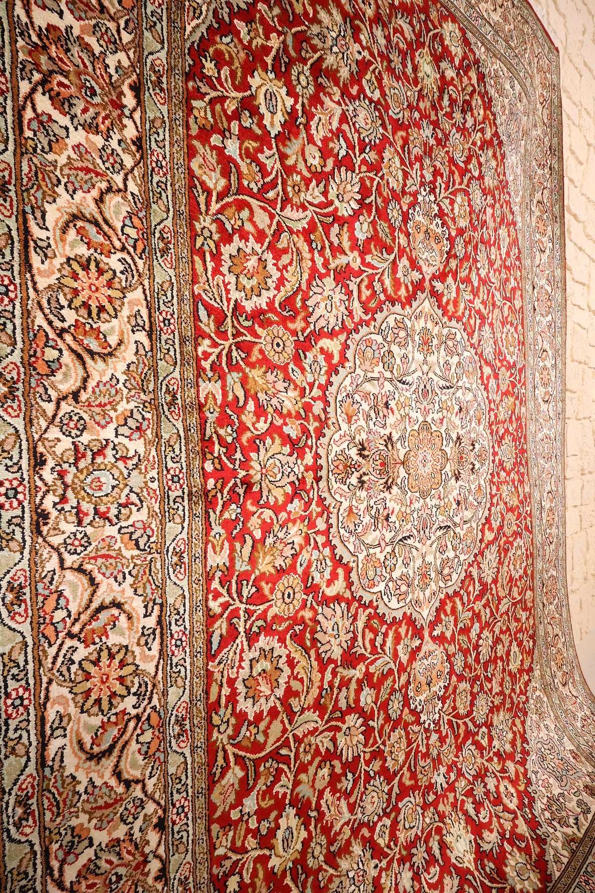 Semis de rinceaux fleuris beige et vert sur champ rouge, vue rapprochée du tapis Cachemire