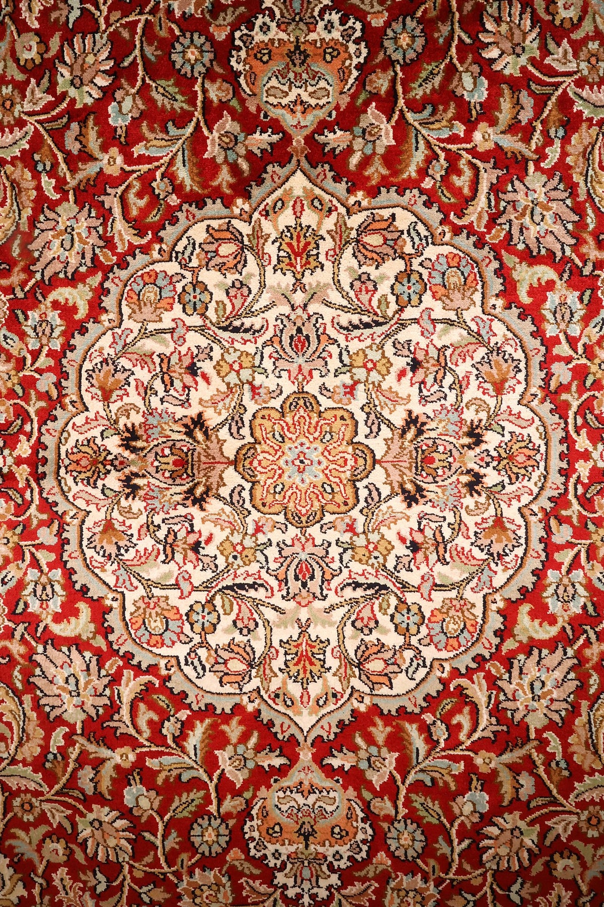 Détail du médaillon ovale ivoire à rosace centrale du tapis Cachemire rouge