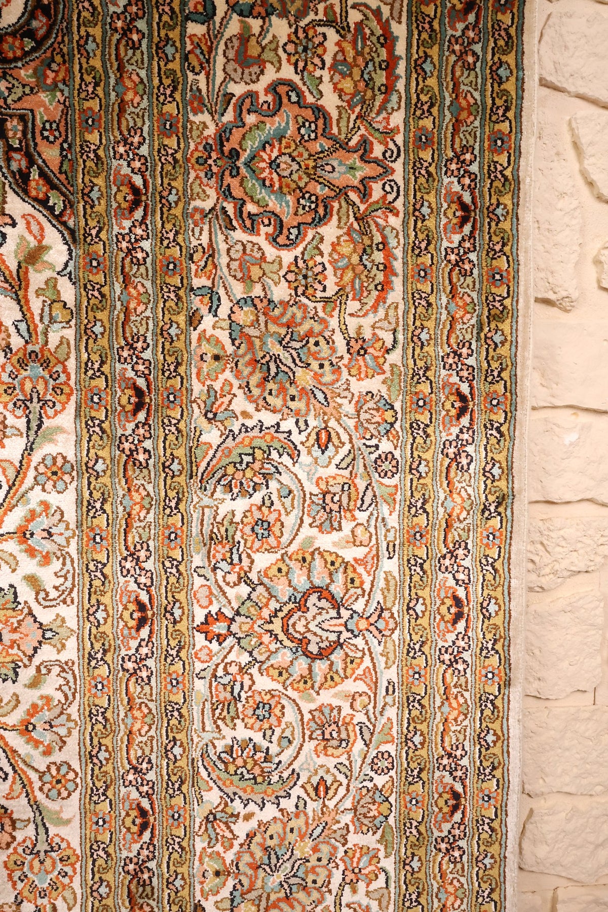 Détail de la bordure beige à rinceaux floraux et contre-bordures jaunes du tapis Cachemire