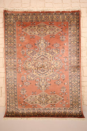 Tapis Caucase rose 176 × 128 cm, vue d'ensemble avec médaillon central étoilé beige